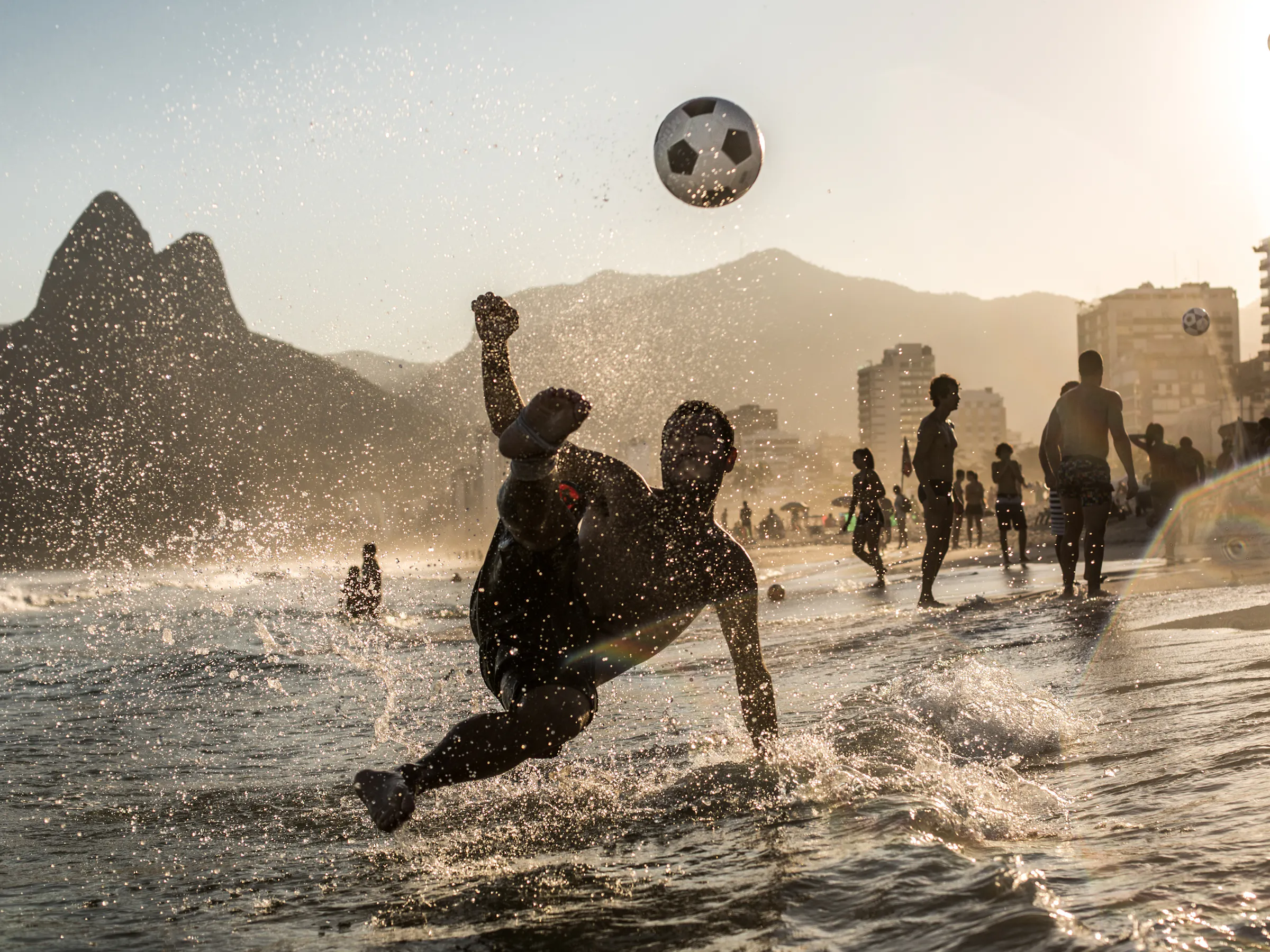 Player bicycle kick on Ipanema Beach with Dois Irmãos mountain, Rio de Janeiro Brazil