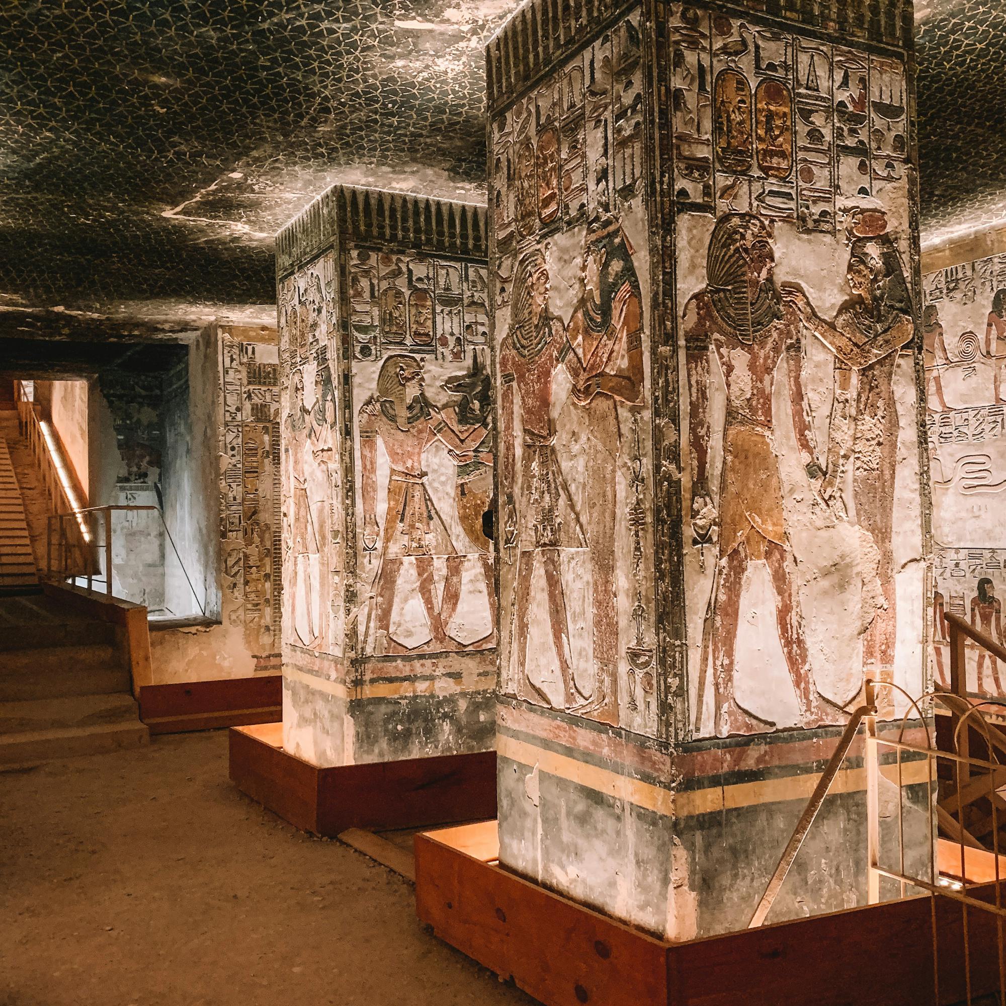Painted pillars and walls line an ancient stone corridor lit by warm ceiling lights.