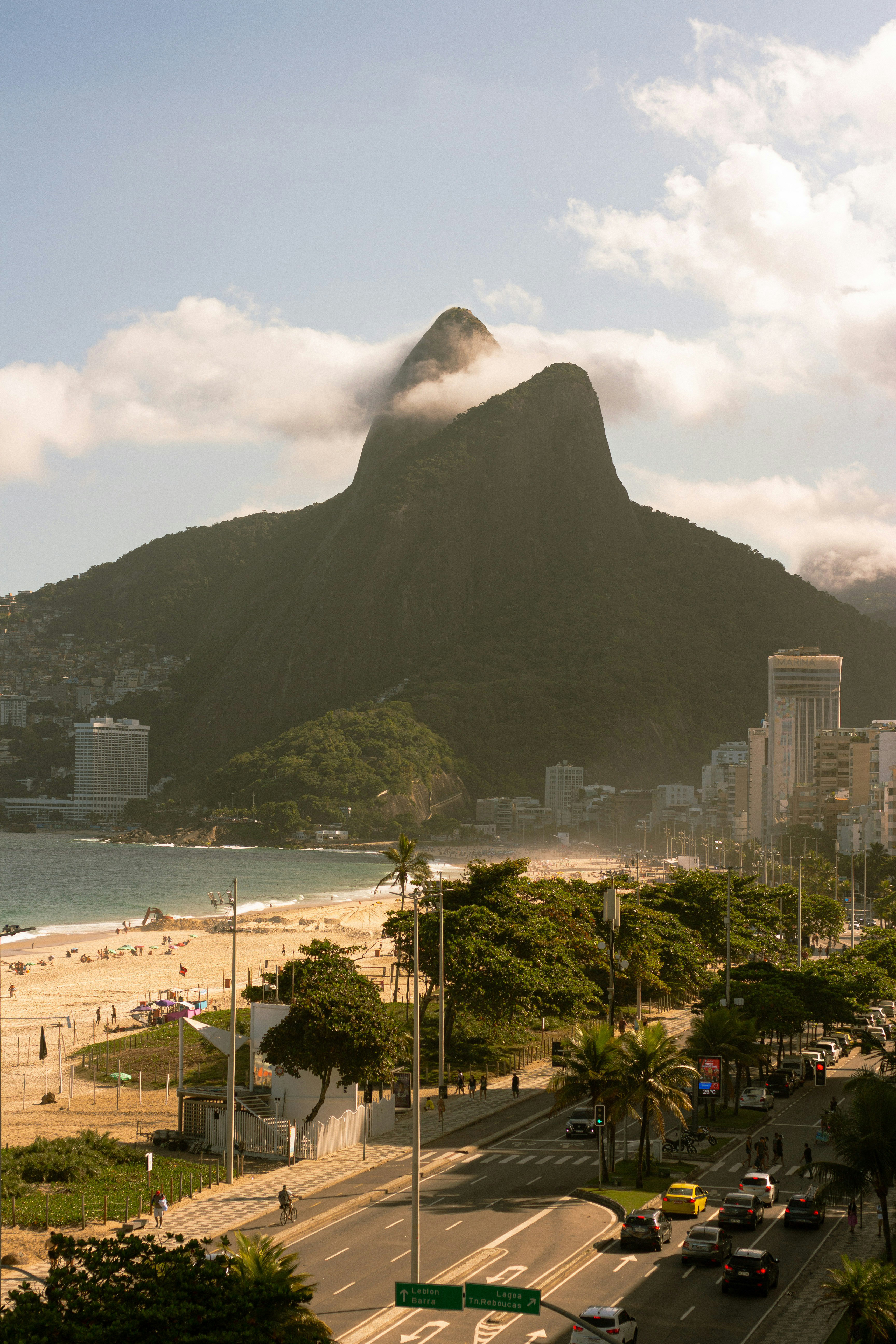View over a coastal city with mountains rising behind, as late sunlight warms buildings and hillsides below near the bay.