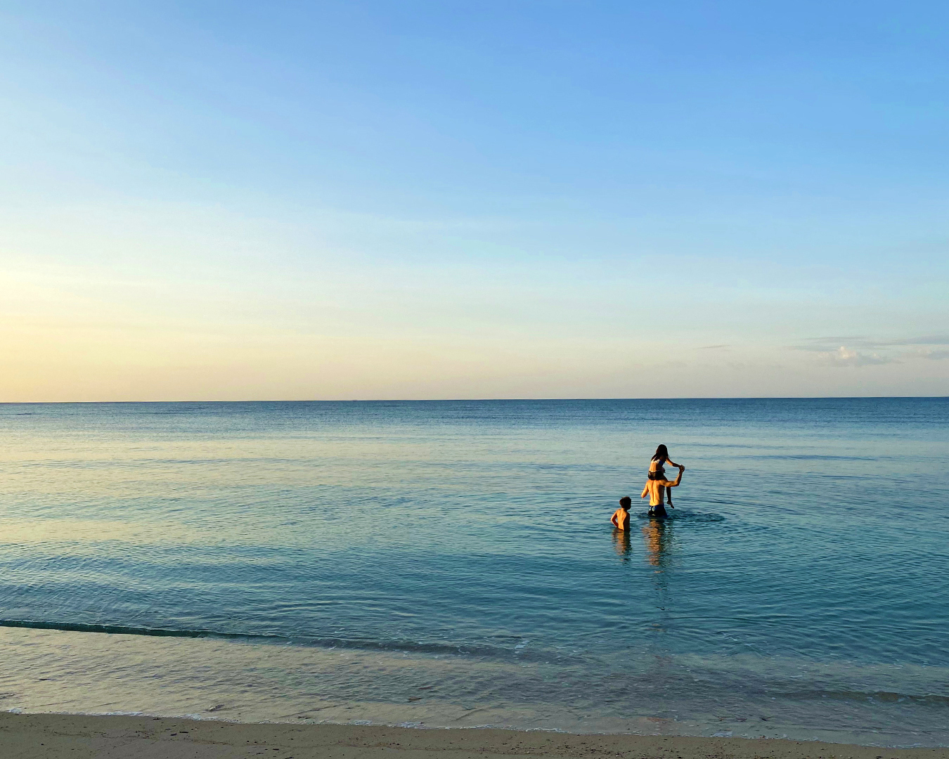 Person stands on calm ocean water with a paddle as the horizon fades into the distance.