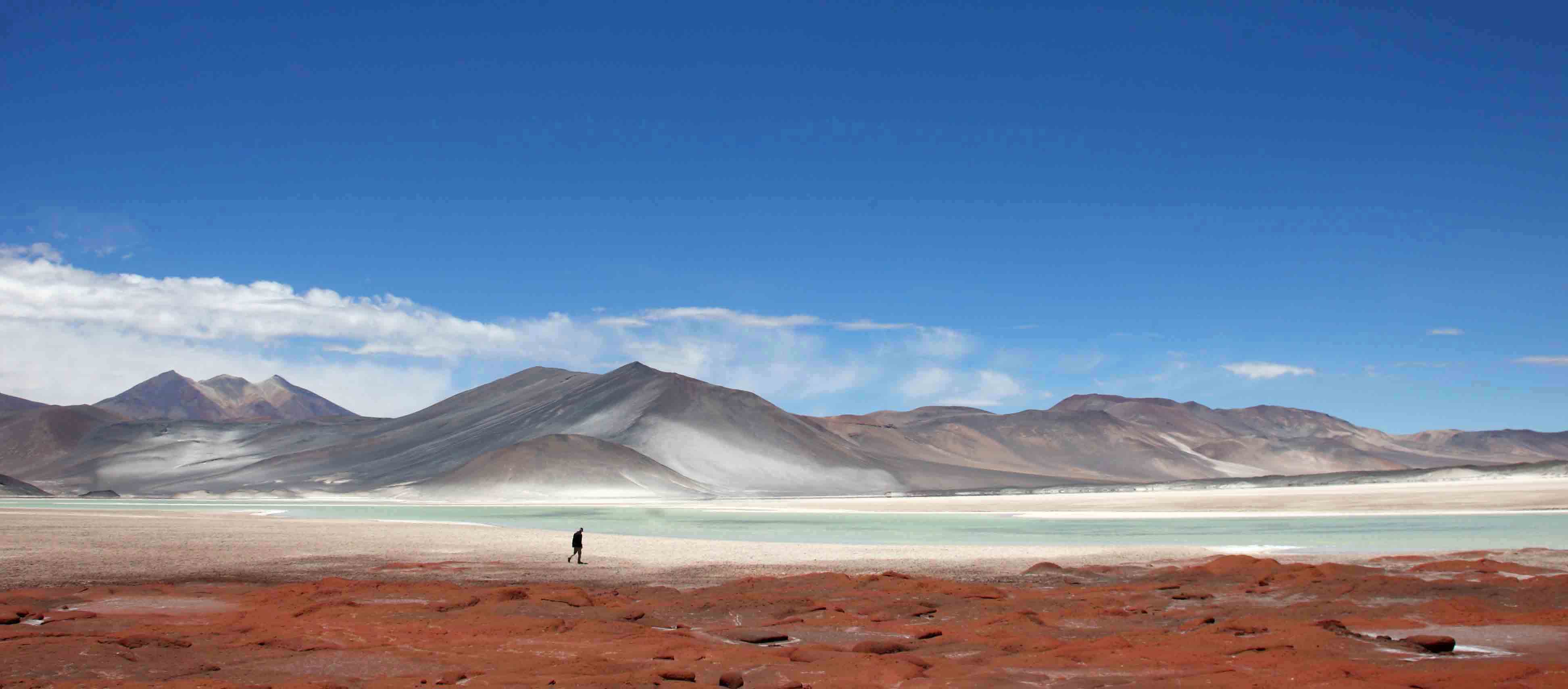Wide desert plain stretches toward distant mountains under a deep blue sky.