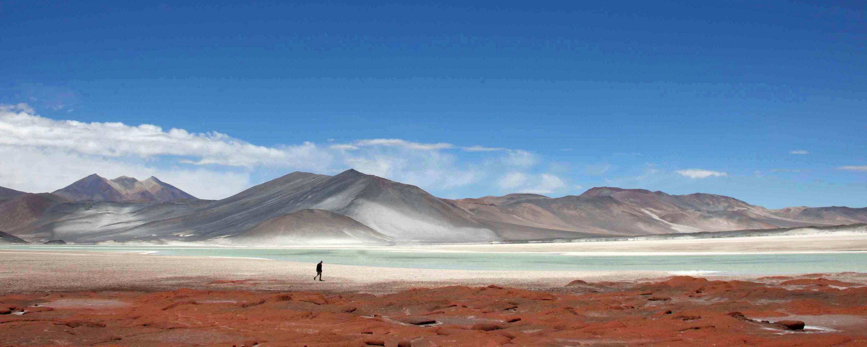Wide desert plain stretches toward distant mountains under a deep blue sky.