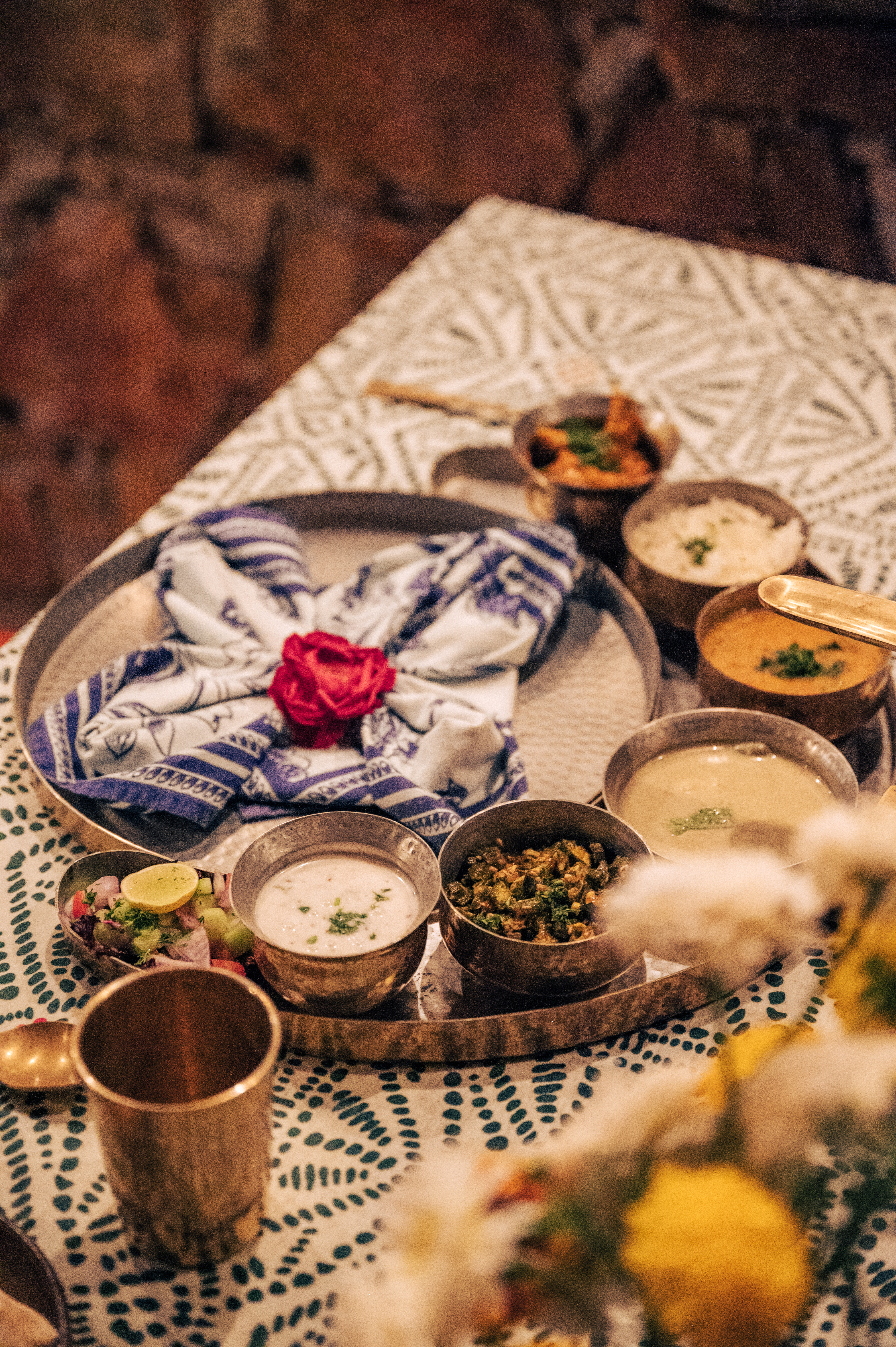 Table set with dishes, bowls, and flowers on patterned textiles.