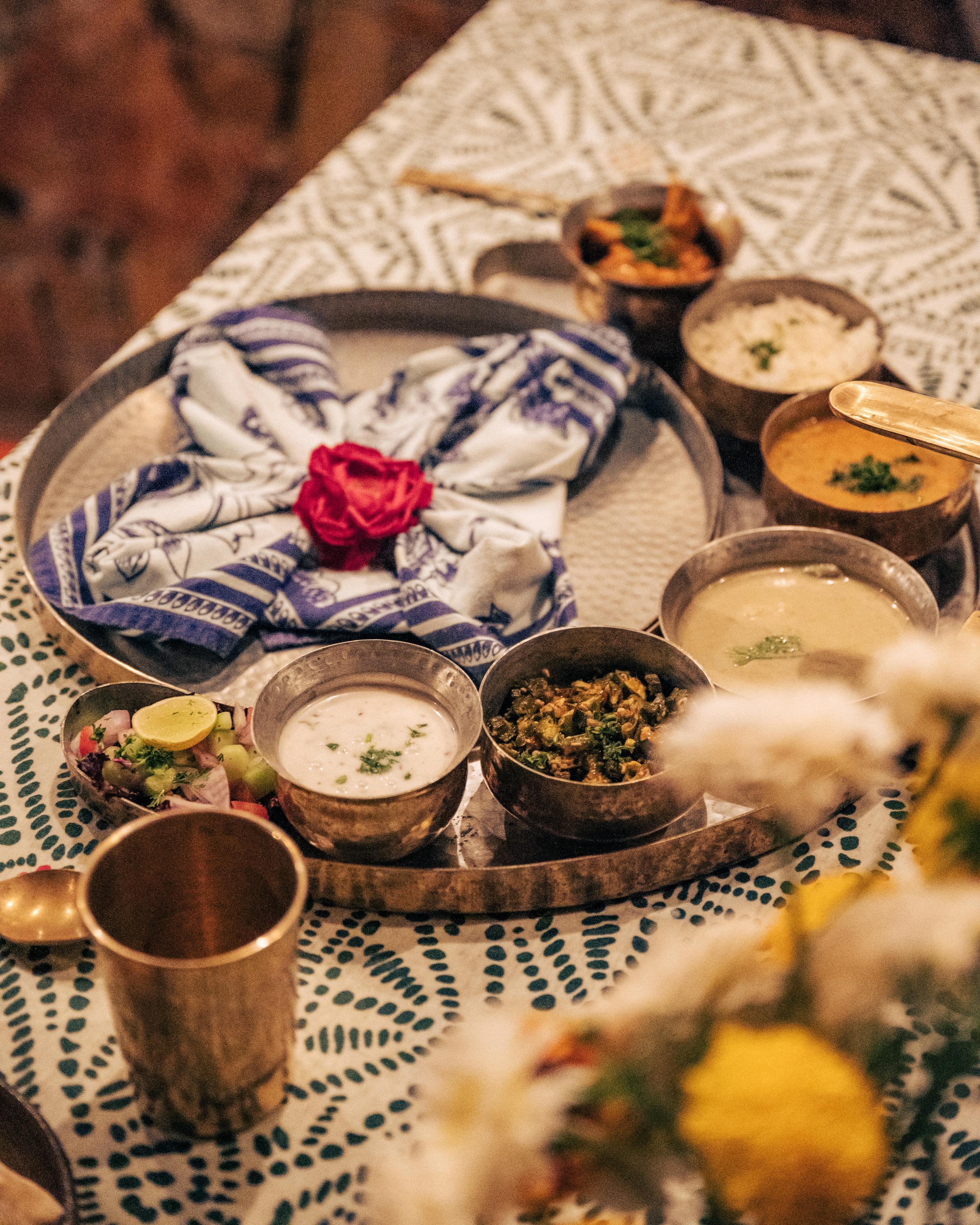 Table set with dishes, bowls, and flowers on patterned textiles.
