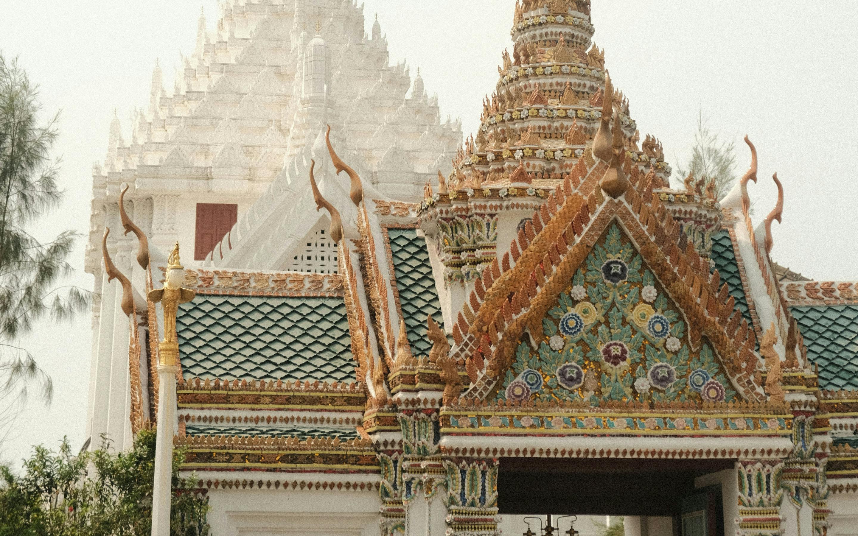 Temple spires rise above ornate rooftops in a palace complex under a hazy sky.