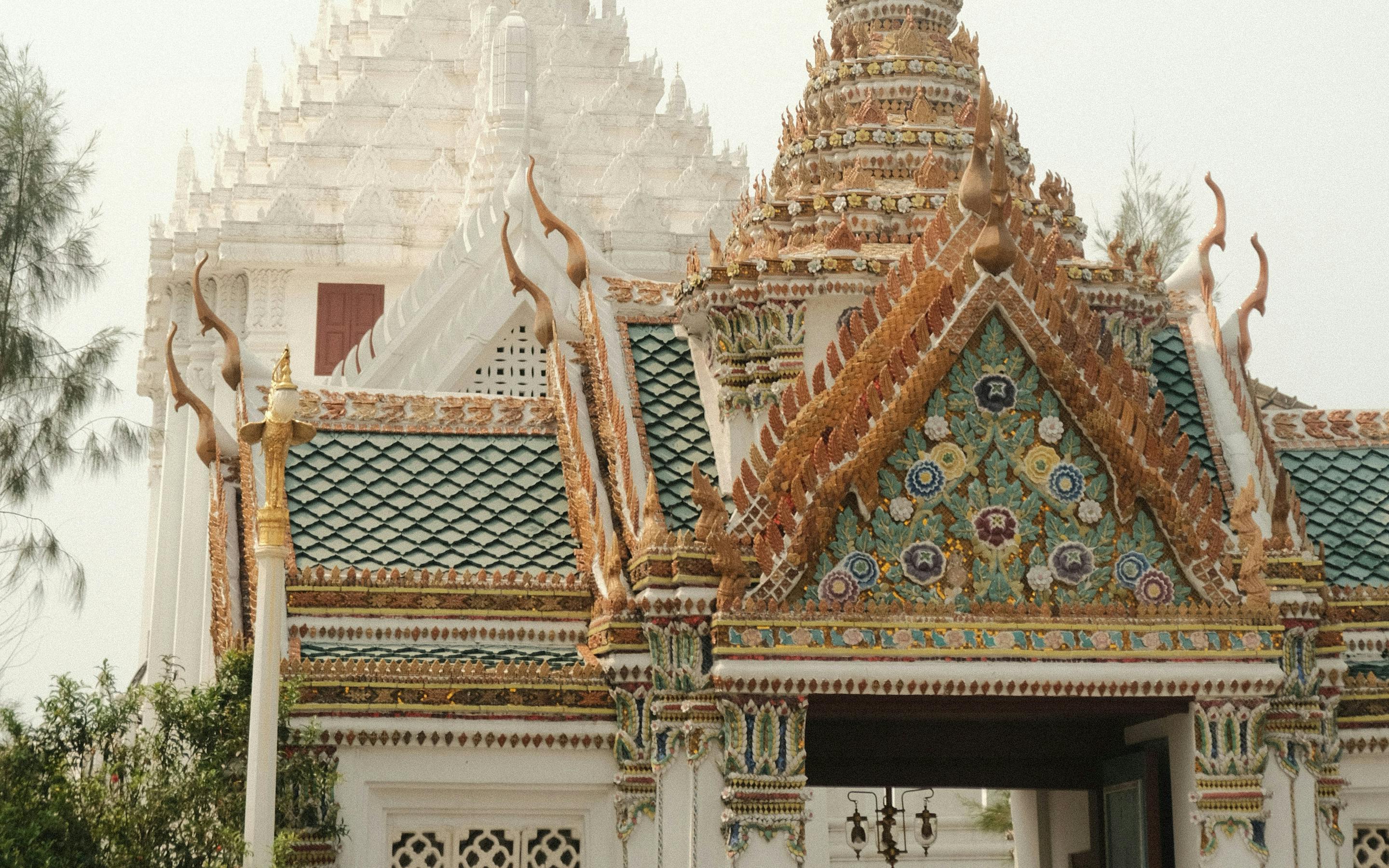Temple spires rise above ornate rooftops in a palace complex under a hazy sky.
