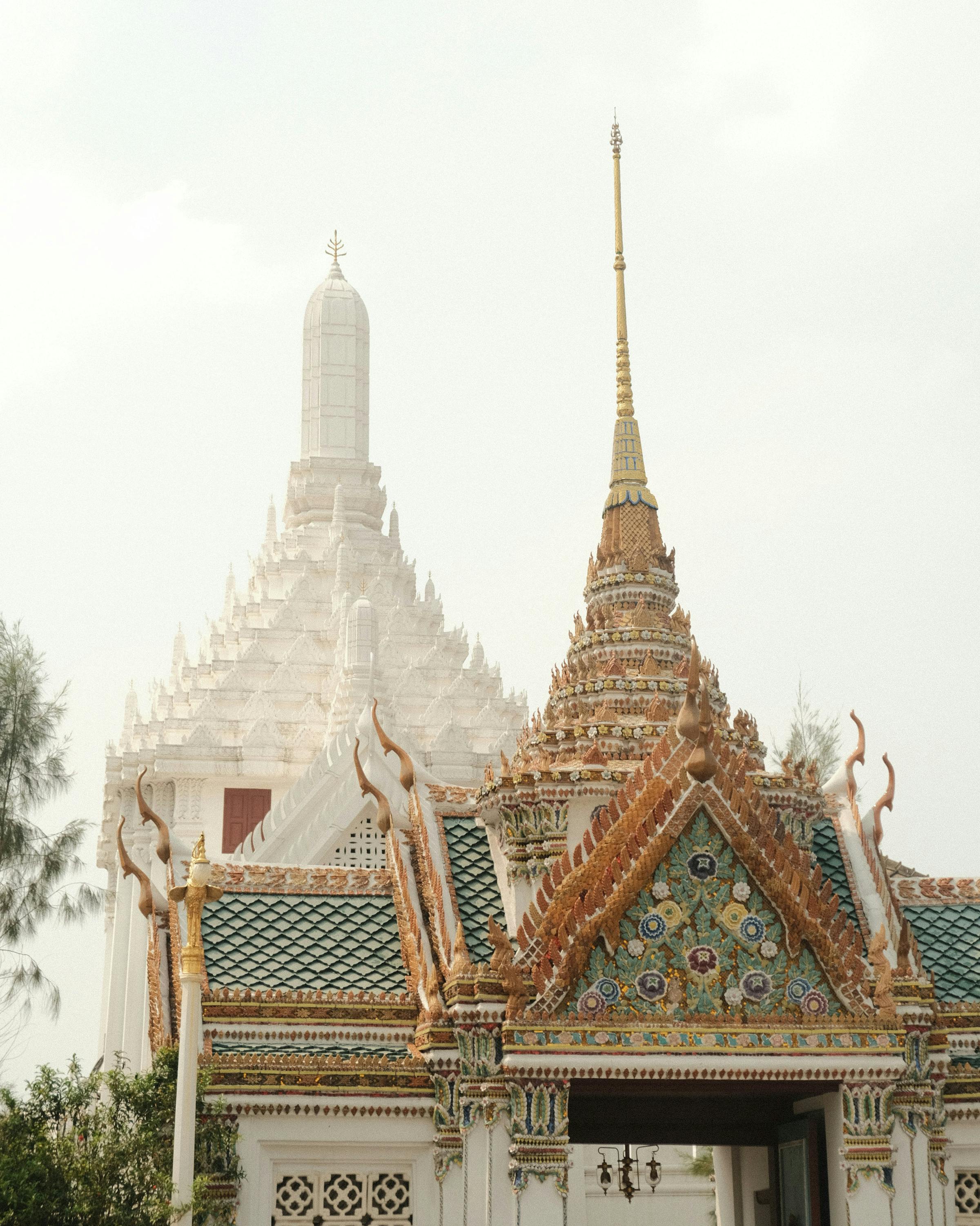 Temple spires rise above ornate rooftops in a palace complex under a hazy sky.