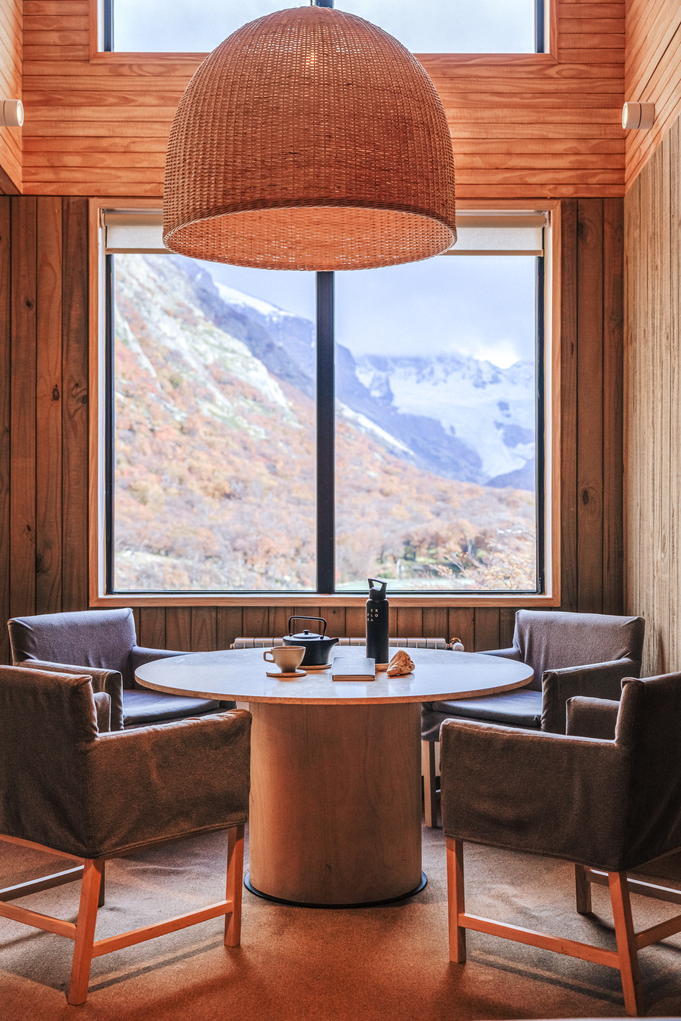 Seating area with two chairs faces a window view of mountains under soft daylight.