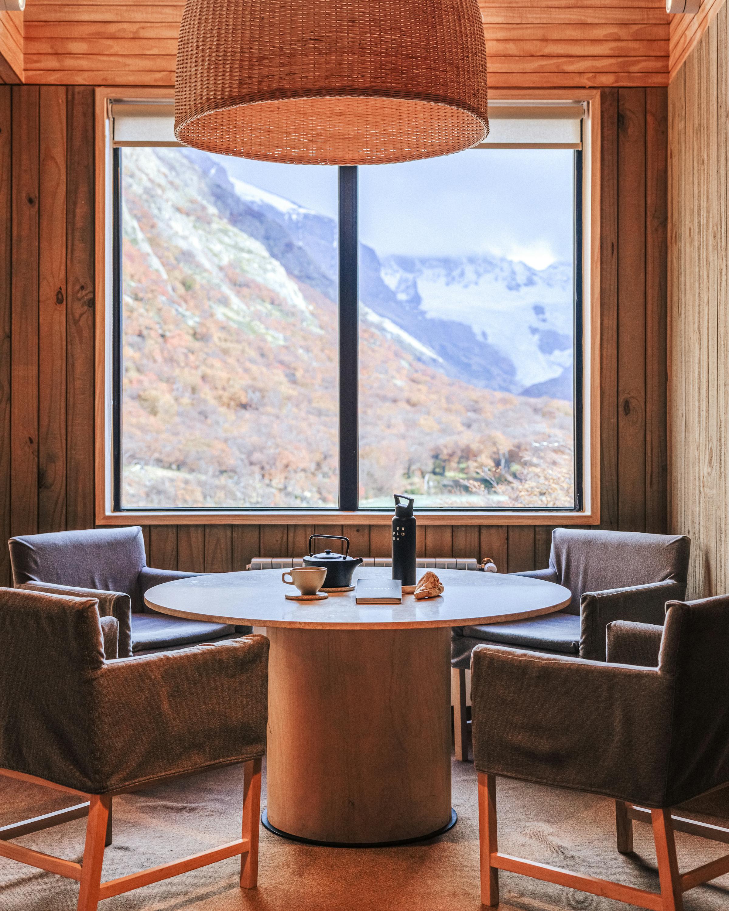 Seating area with two chairs faces a window view of mountains under soft daylight.