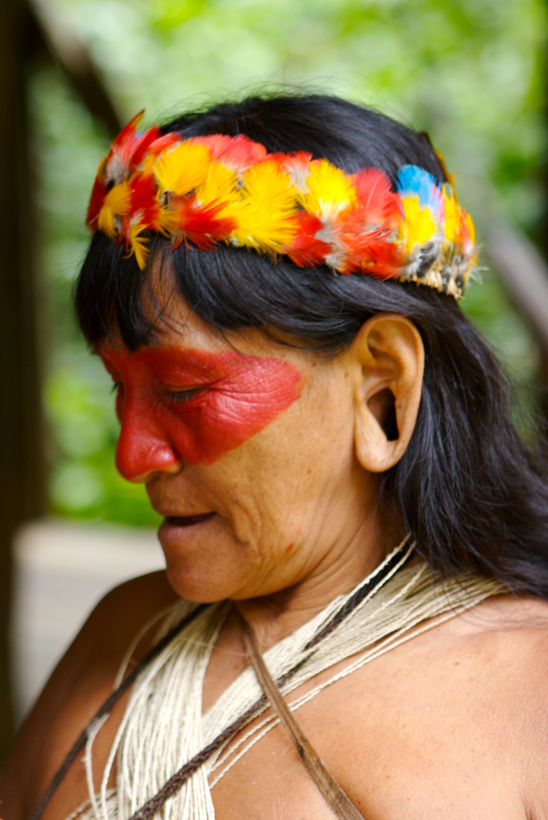 Close-up of a person with red face paint wearing a colorful headband.