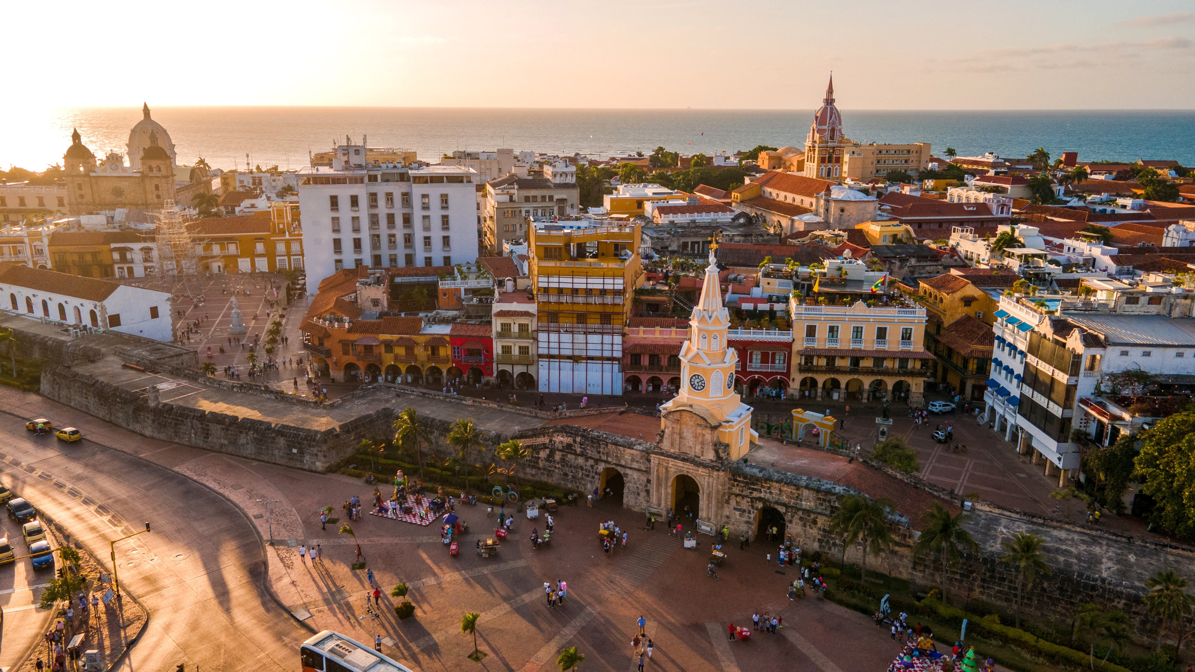 Aerial view of a historic city center with plazas and rooftops in warm evening light.