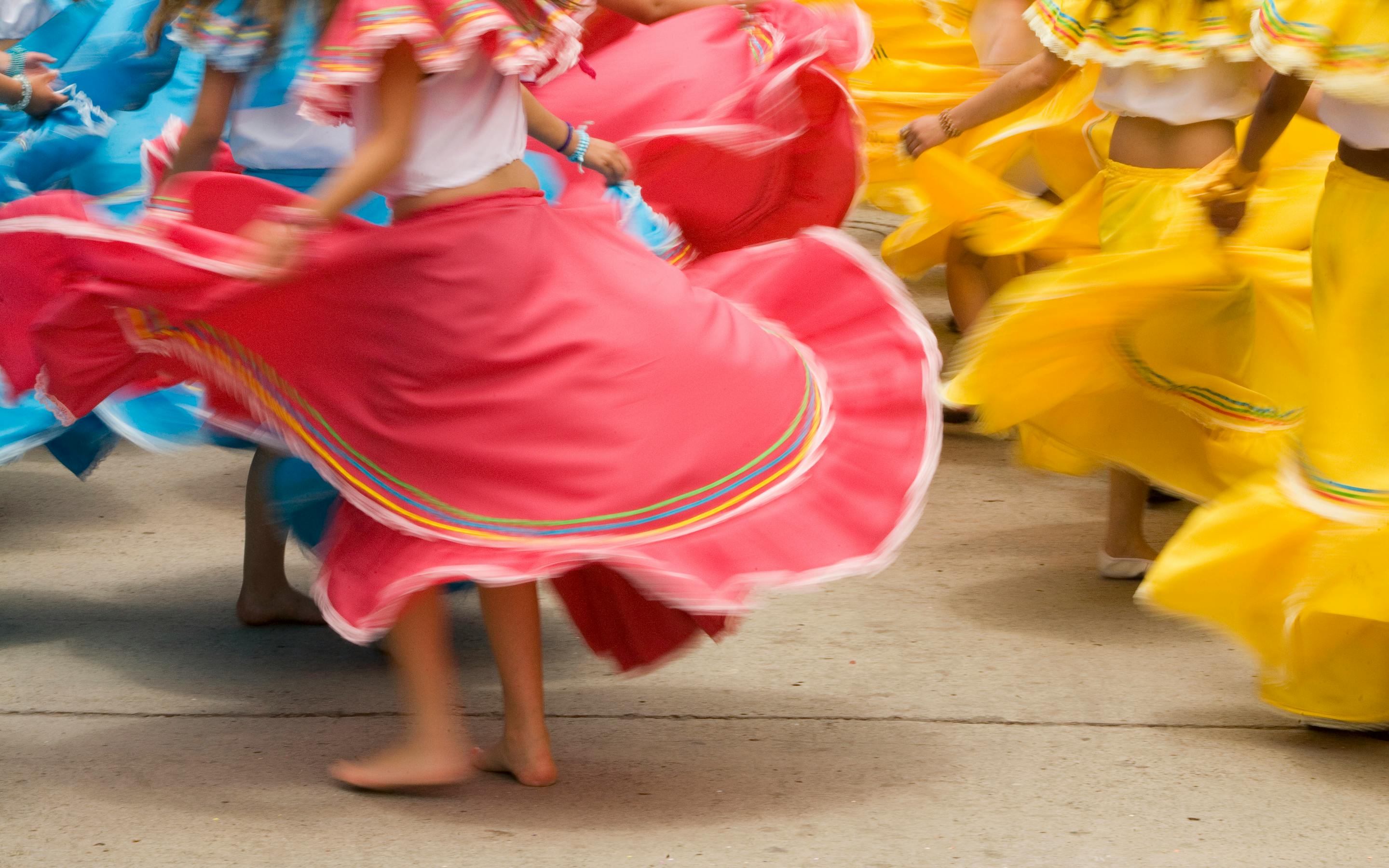 Dancers in colorful skirts spin, creating bright swirls of fabric.