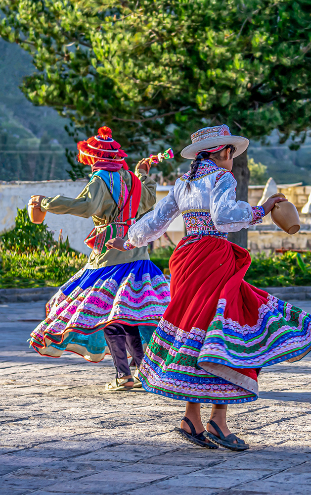 Dancer in a colorful skirt twirls in an outdoor courtyard.