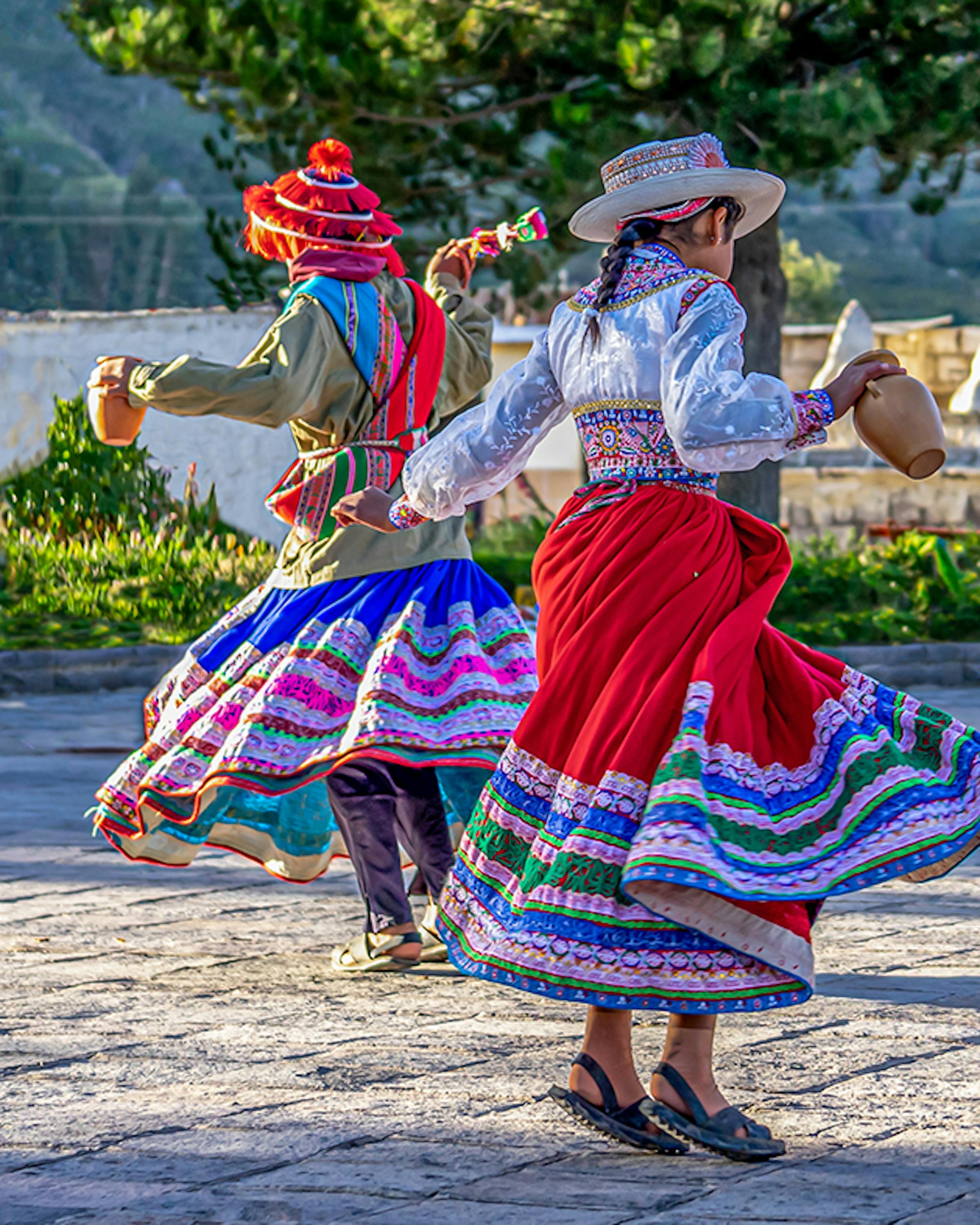 Dancer in a colorful skirt twirls in an outdoor courtyard.