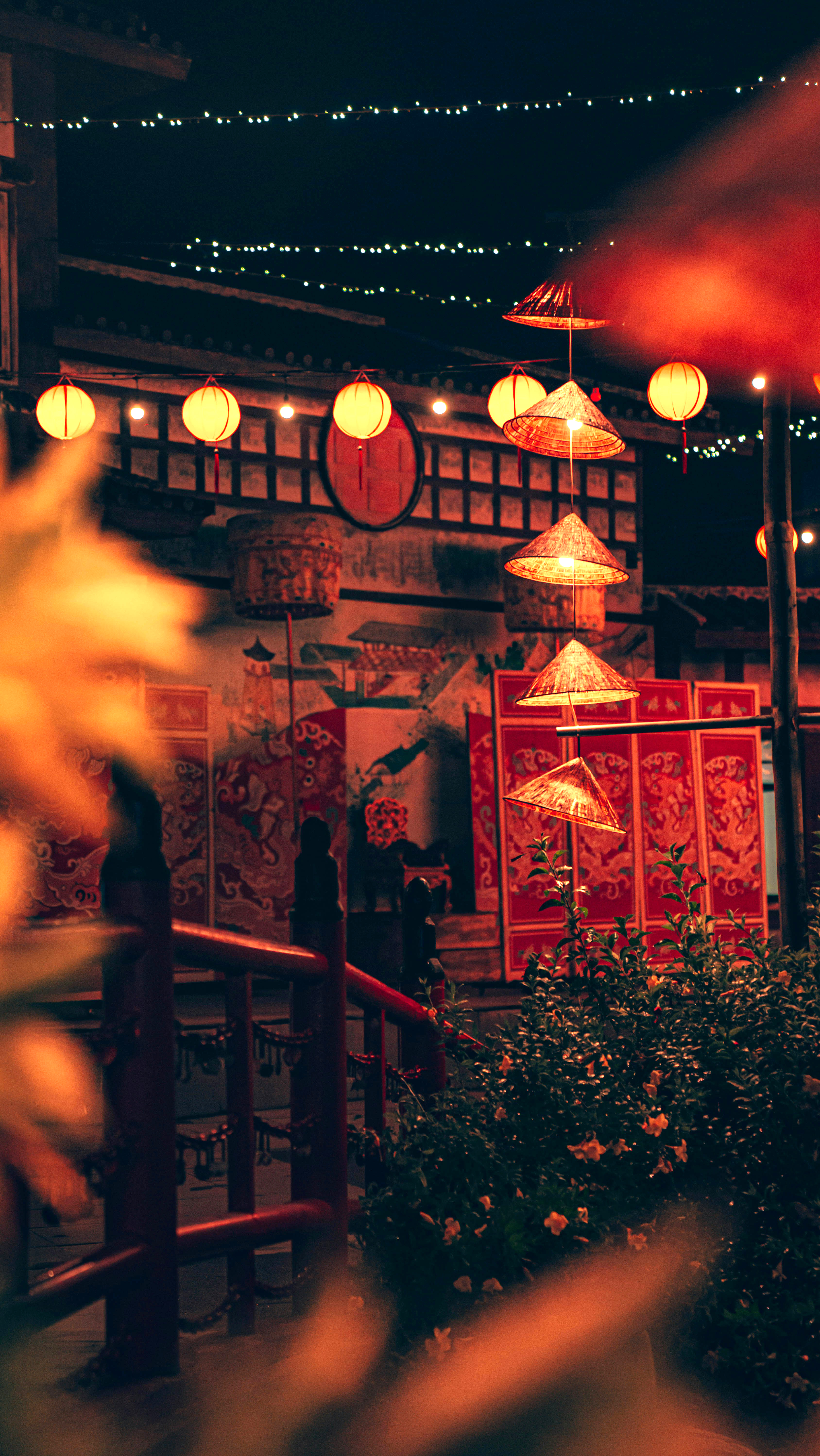 Lantern-lit restaurant scene at night, with glowing lights, wooden beams, and diners seated inside under soft daylight.