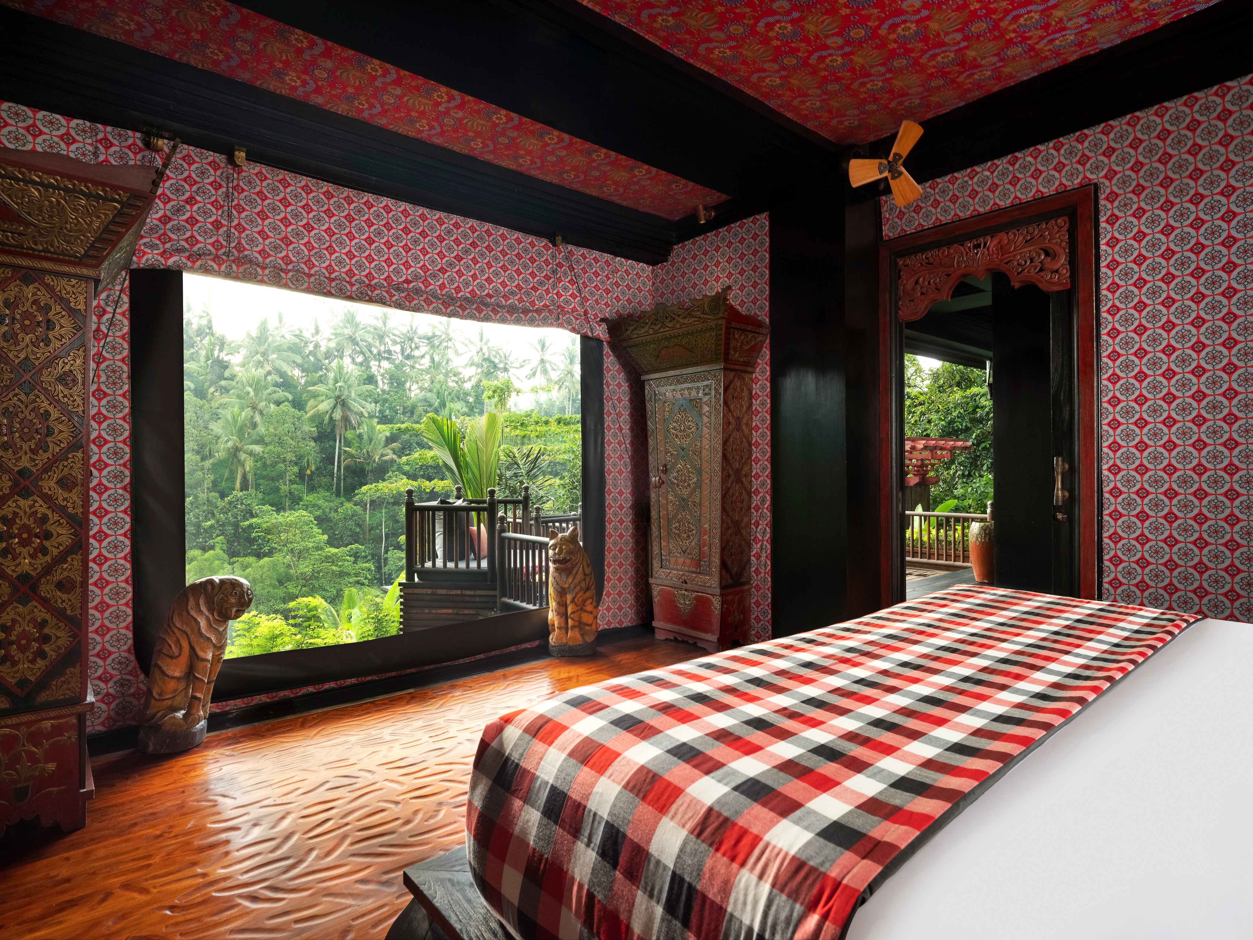Bedroom opens through wide doors to lush greenery, with patterned textiles and warm wood interior details.