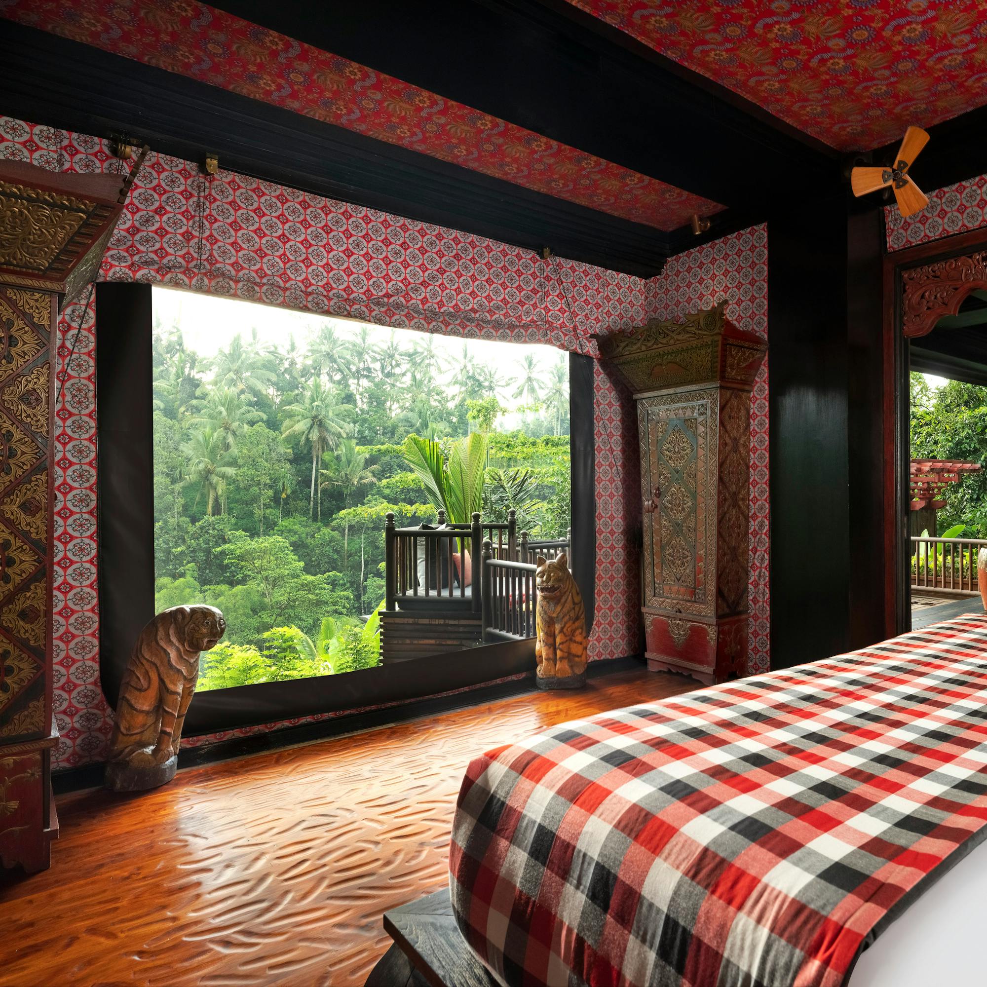Bedroom opens through wide doors to lush greenery, with patterned textiles and warm wood interior details.