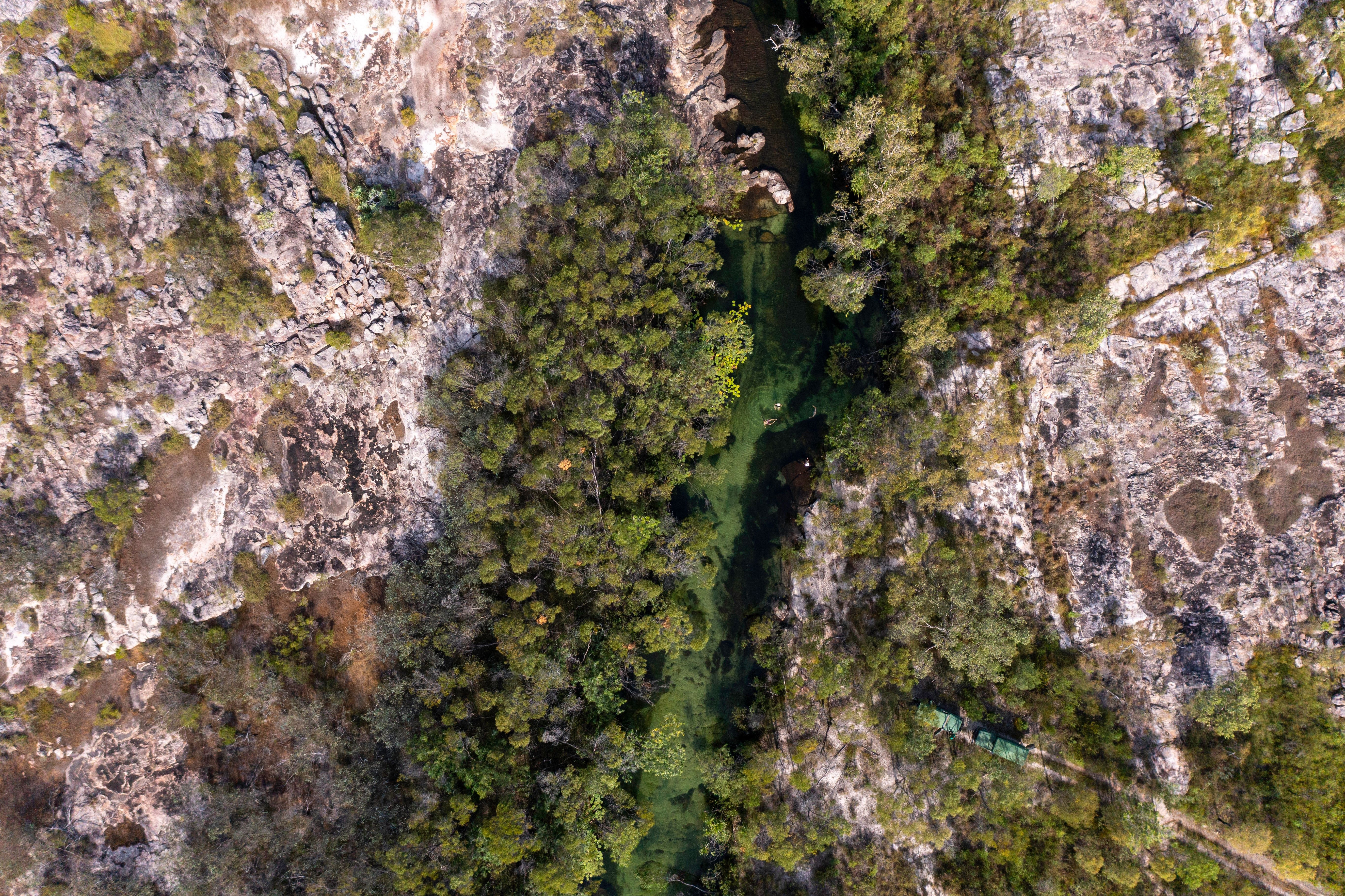 Aerial view of a winding river cutting through green floodplains, with braided channels and sandbars below.