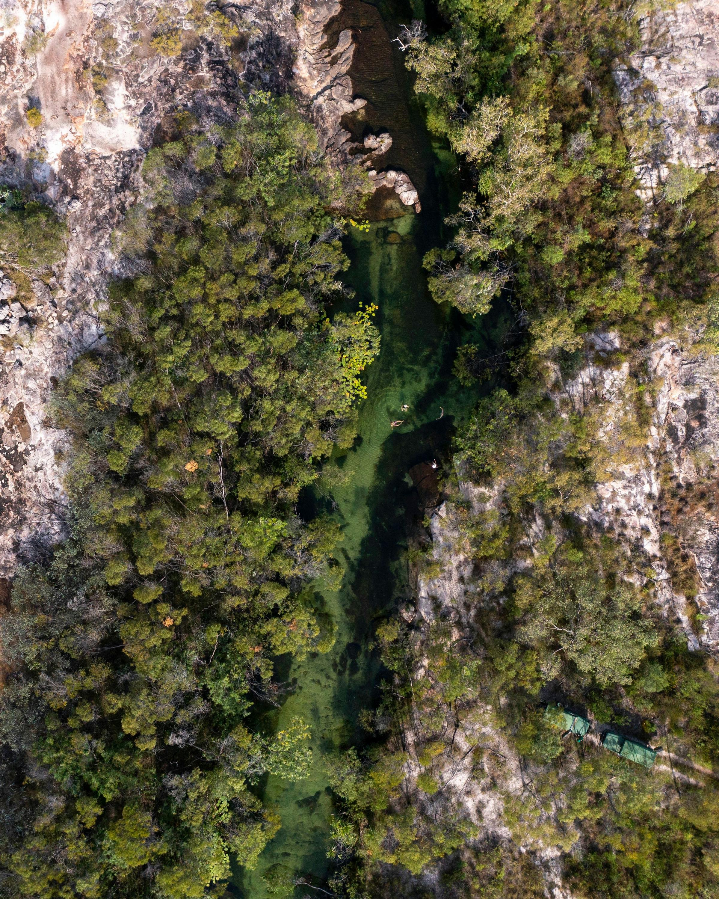 Aerial view of a winding river cutting through green floodplains, with braided channels and sandbars below.