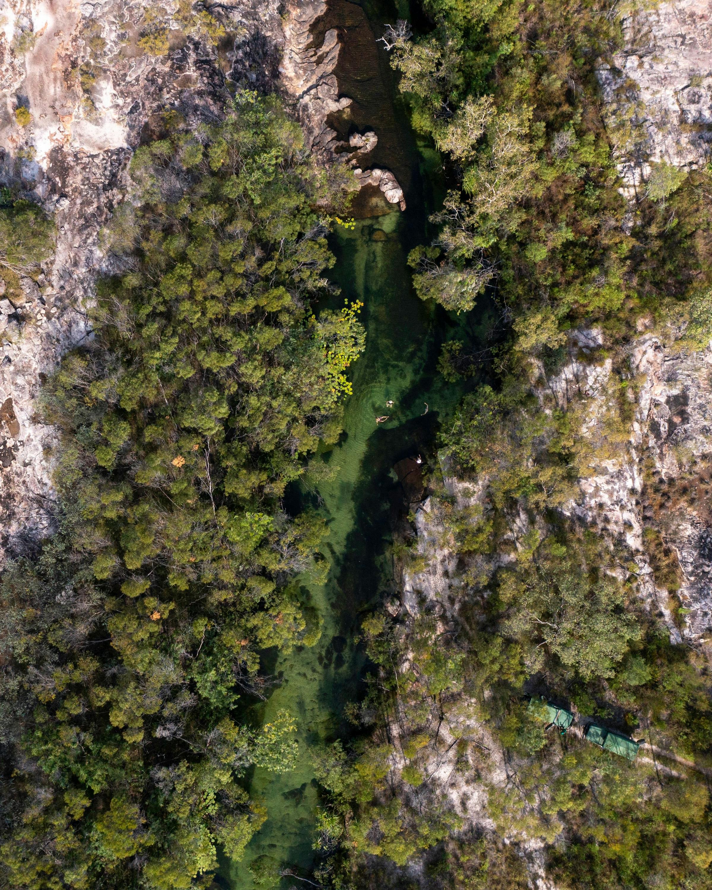Aerial view of a winding river cutting through green floodplains, with braided channels and sandbars below.