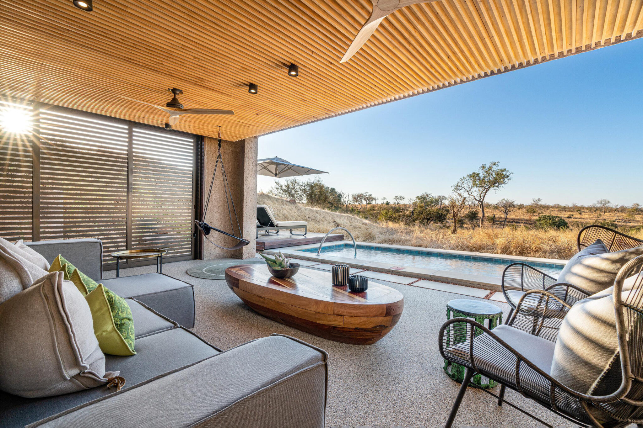 A modern suite terrace with a plunge pool faces open bushland, framed by wood beams and shaded seating outdoors.