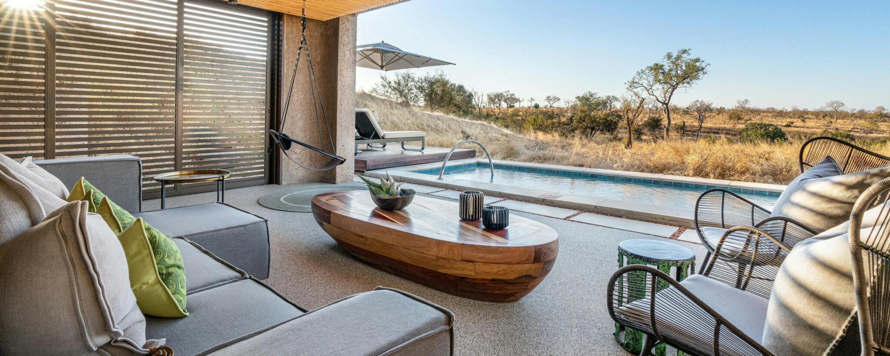 A modern suite terrace with a plunge pool faces open bushland, framed by wood beams and shaded seating outdoors.