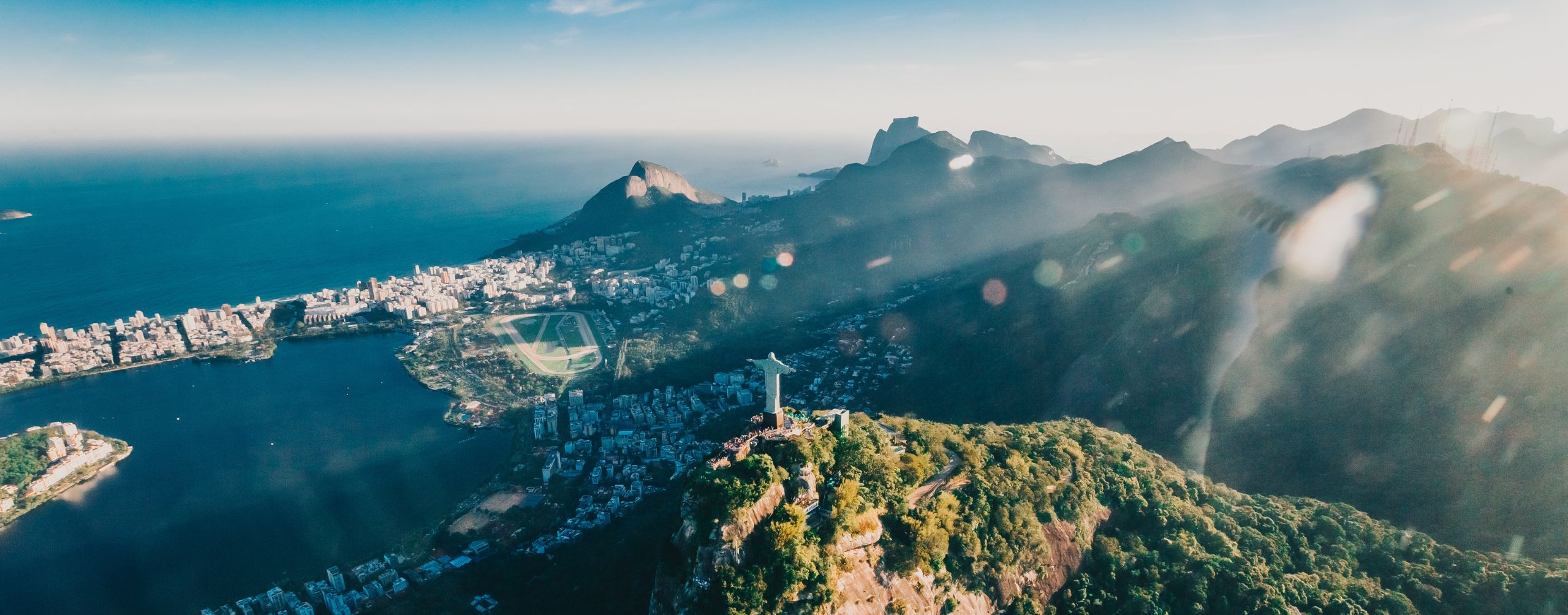 Christ the Redeemer statue stands above Rio de Janeiro, overlooking a sprawling city and bay through low clouds.