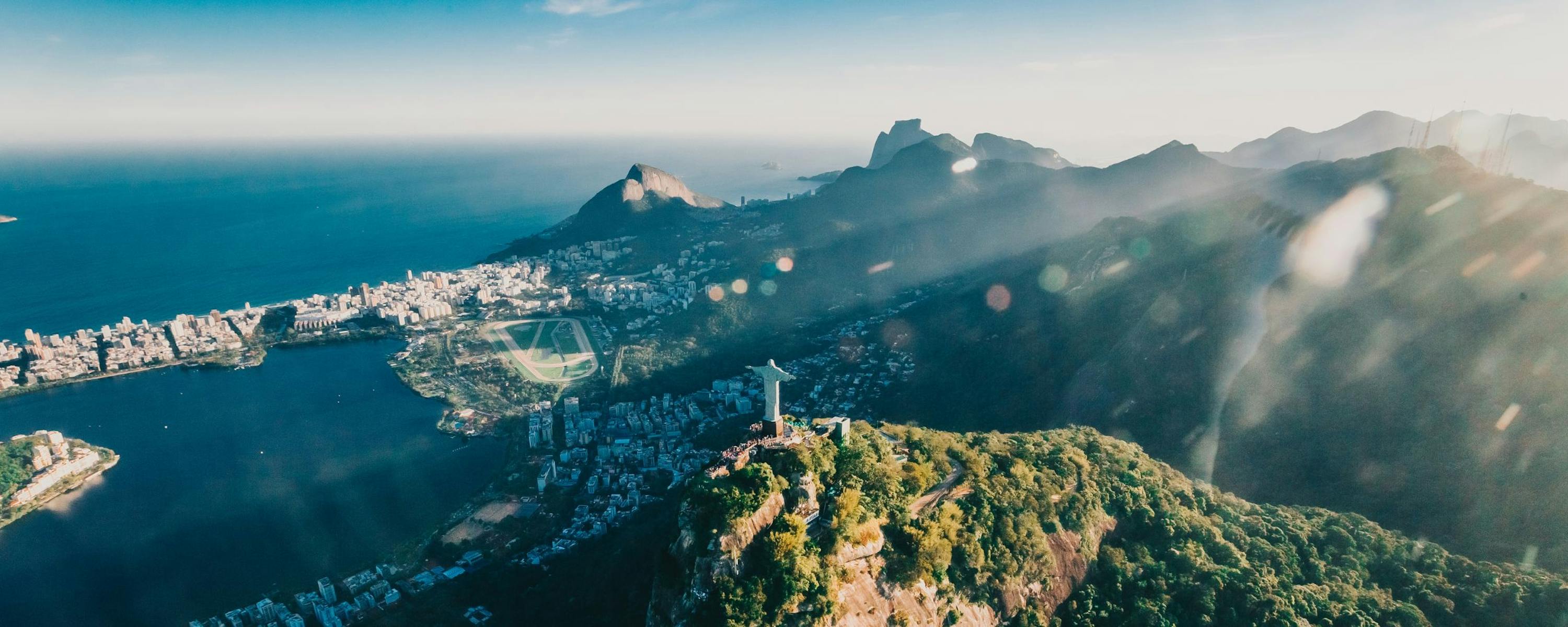 Christ the Redeemer statue stands above Rio de Janeiro, overlooking a sprawling city and bay through low clouds.