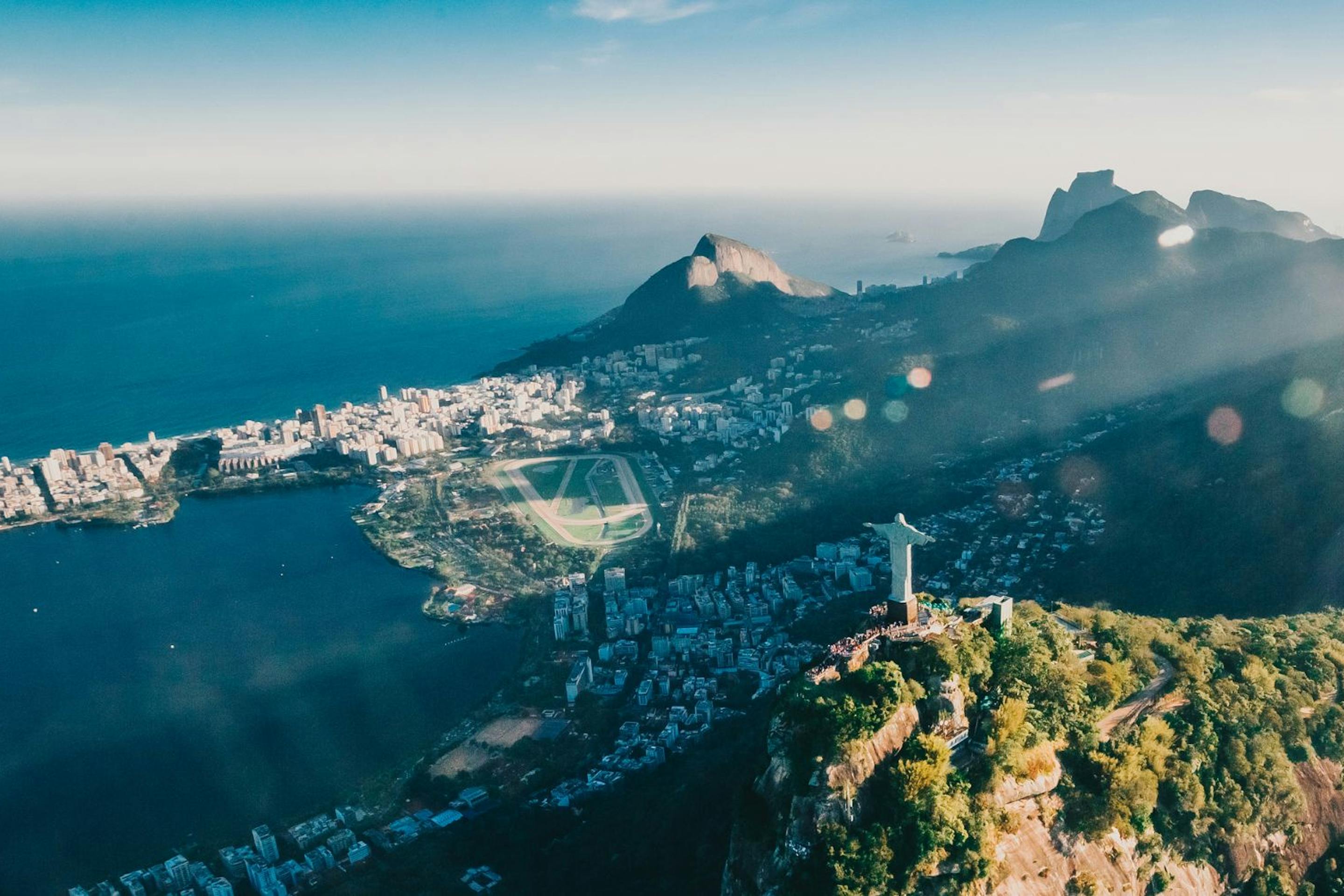 Christ the Redeemer statue stands above Rio de Janeiro, overlooking a sprawling city and bay through low clouds.