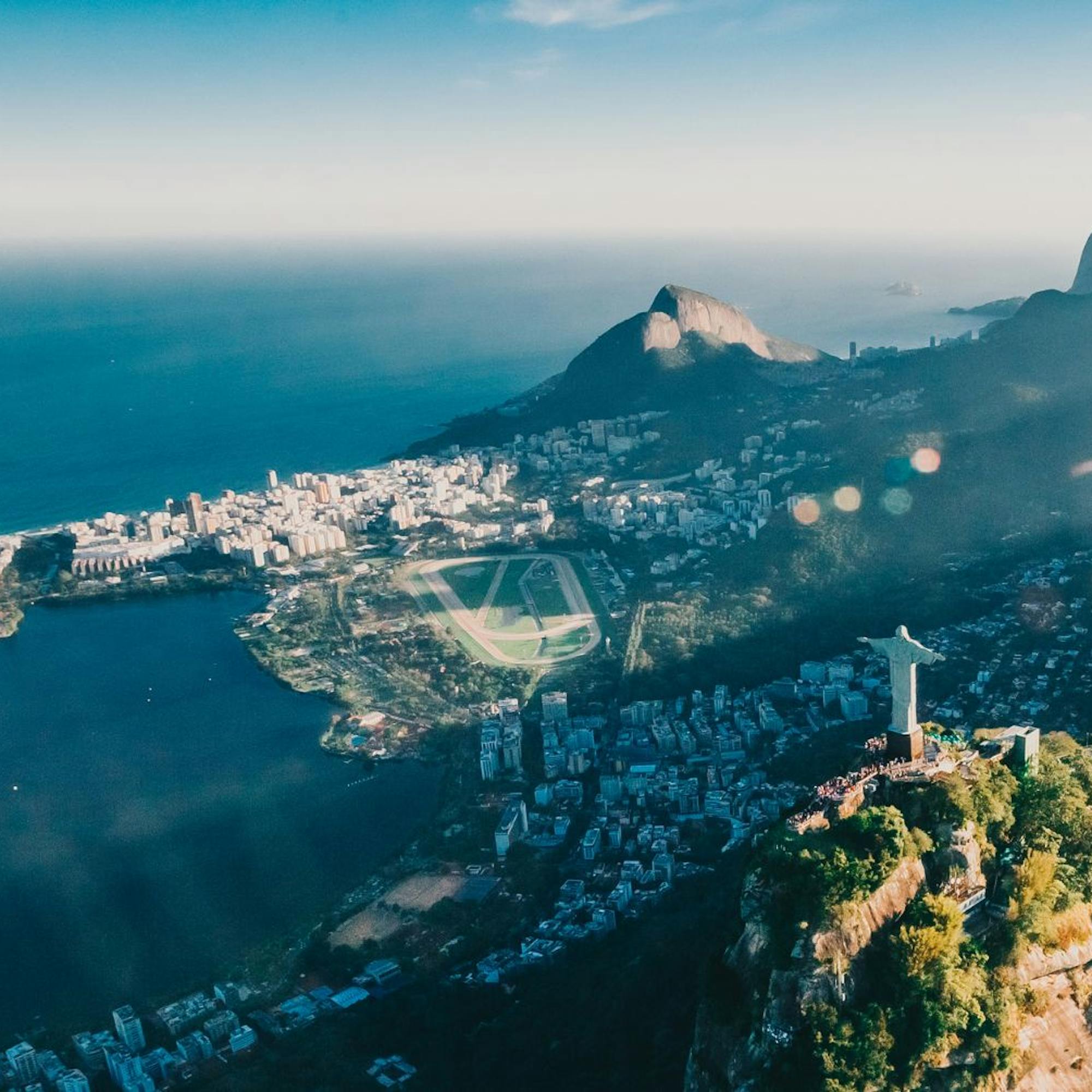 Christ the Redeemer statue stands above Rio de Janeiro, overlooking a sprawling city and bay through low clouds.
