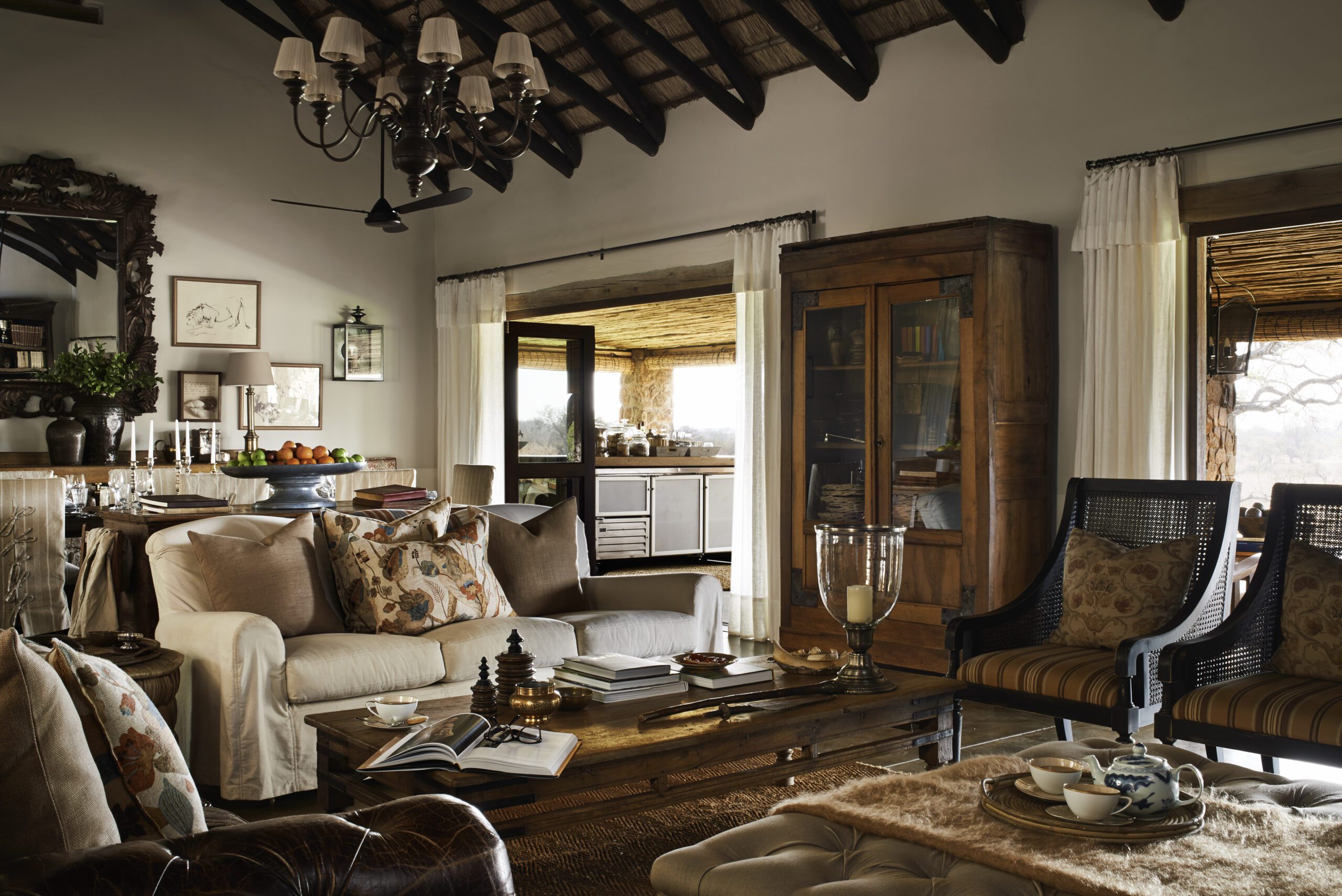 A spacious lodge living room with sofas and warm wood furniture opens to large windows and patterned rugs.