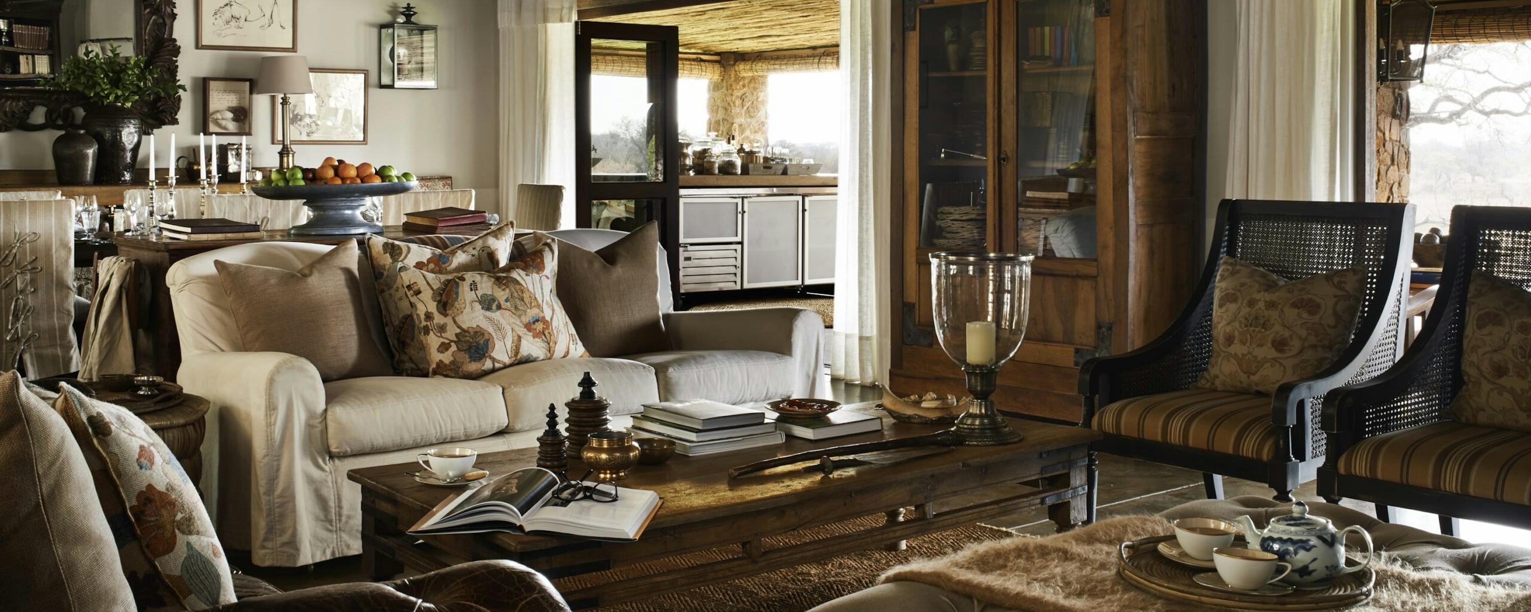 A spacious lodge living room with sofas and warm wood furniture opens to large windows and patterned rugs.