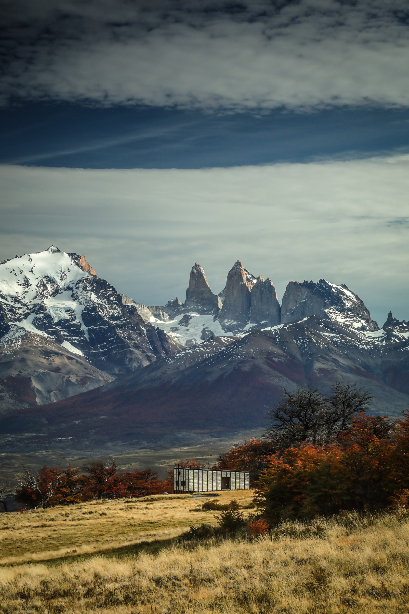 Awasi villas sit on open steppe, each facing the Torres del Paine skyline beneath sweeping cloud cover, in Patagonia..