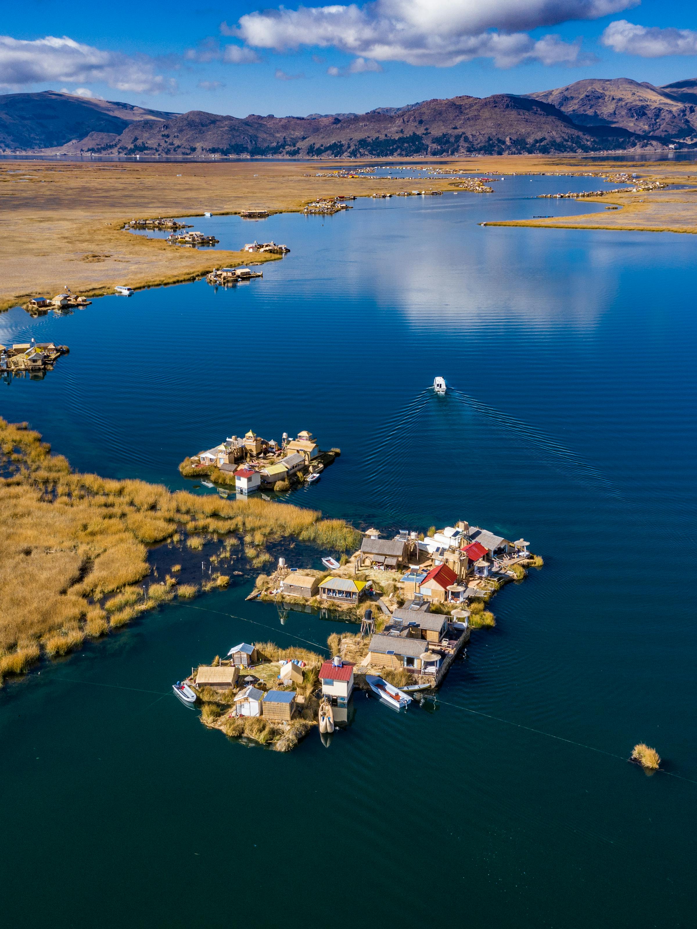 Aerial view of Lake Titicaca shoreline and islands, a small town curving around deep blue water and bays below.