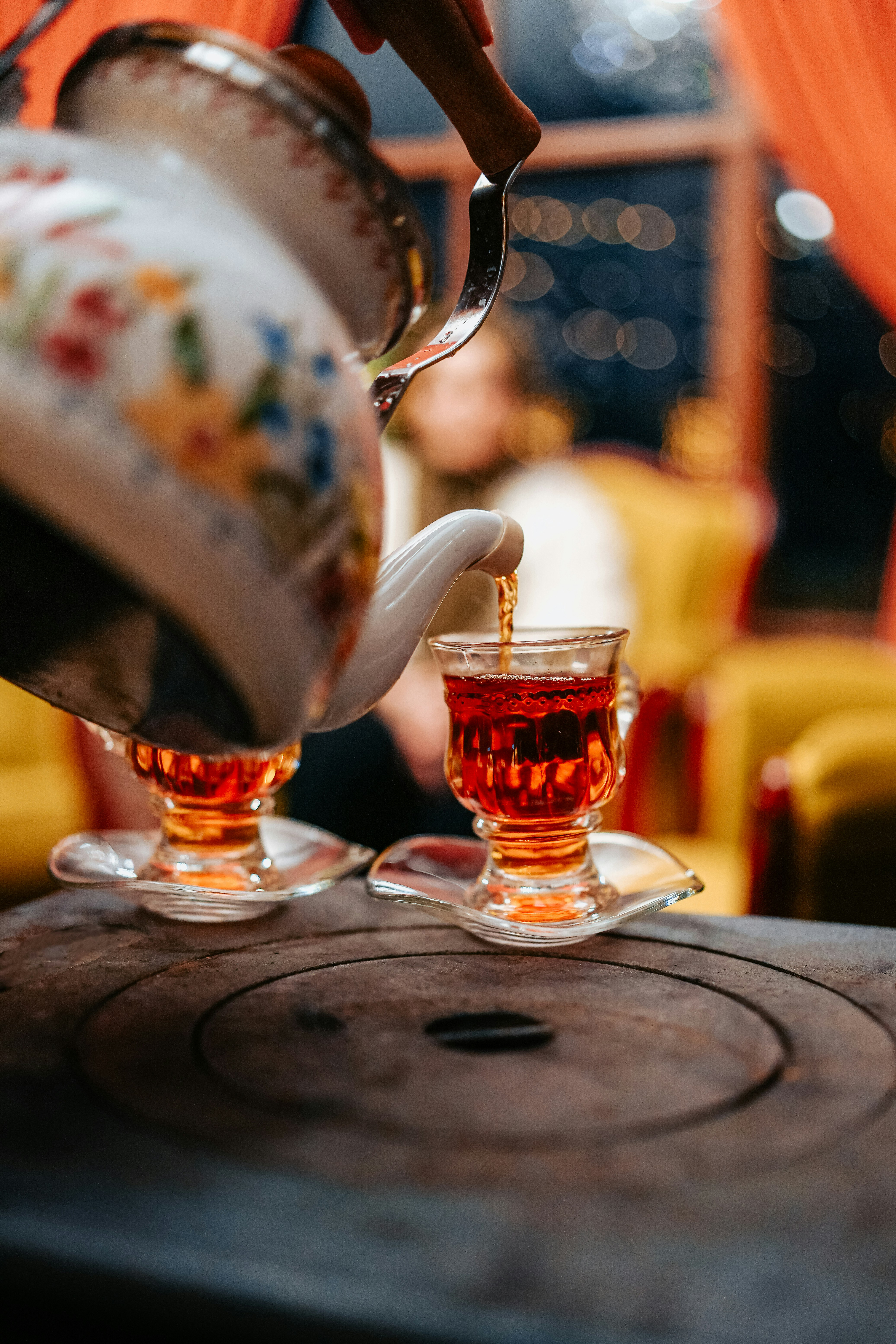 Two glasses of mint tea sit on a café table, amber liquid glowing while a busy market scene blurs behind.