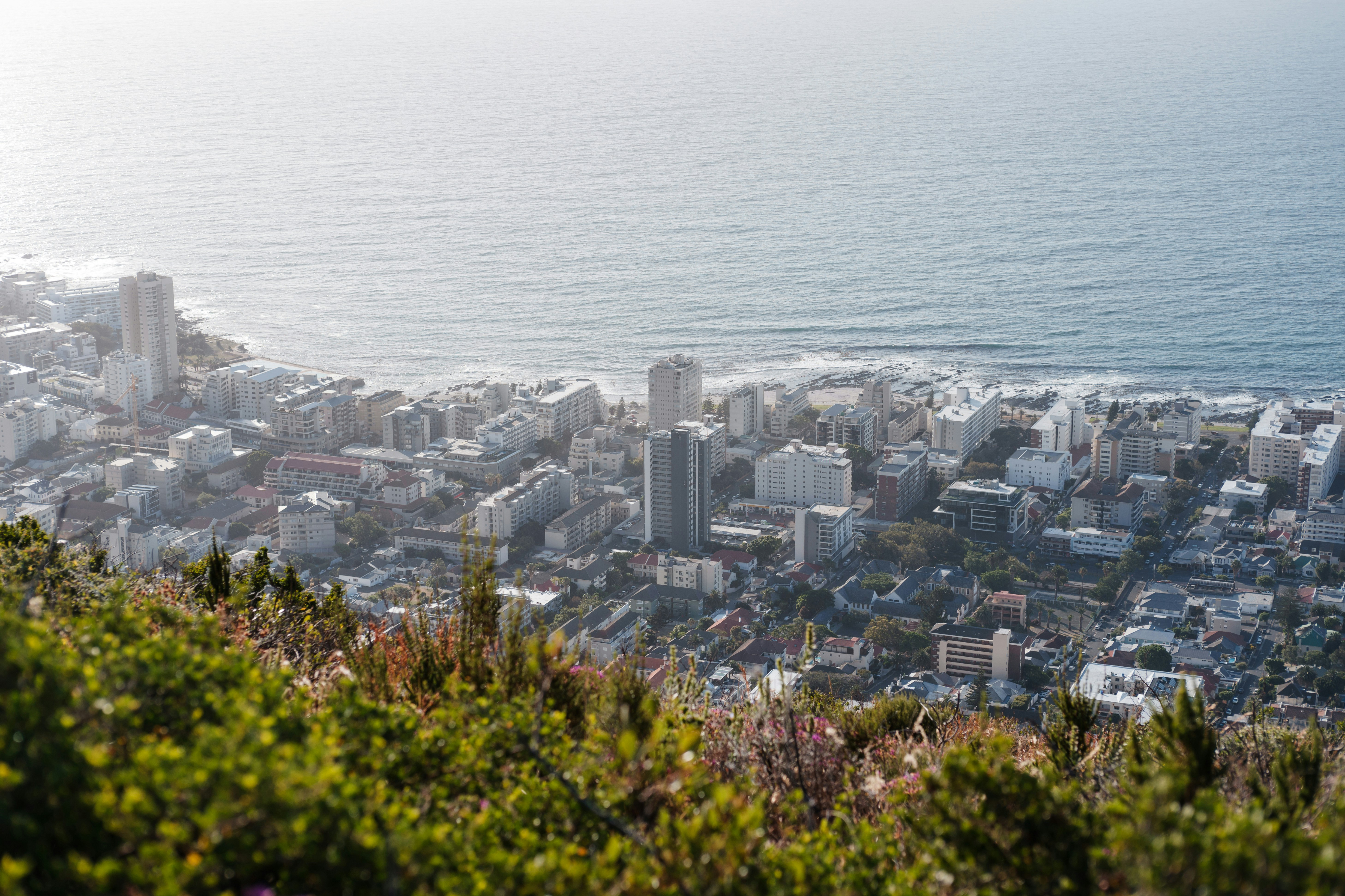 A wide view over Cape Town reveals dense neighborhoods and the Atlantic coastline stretching along the horizon.