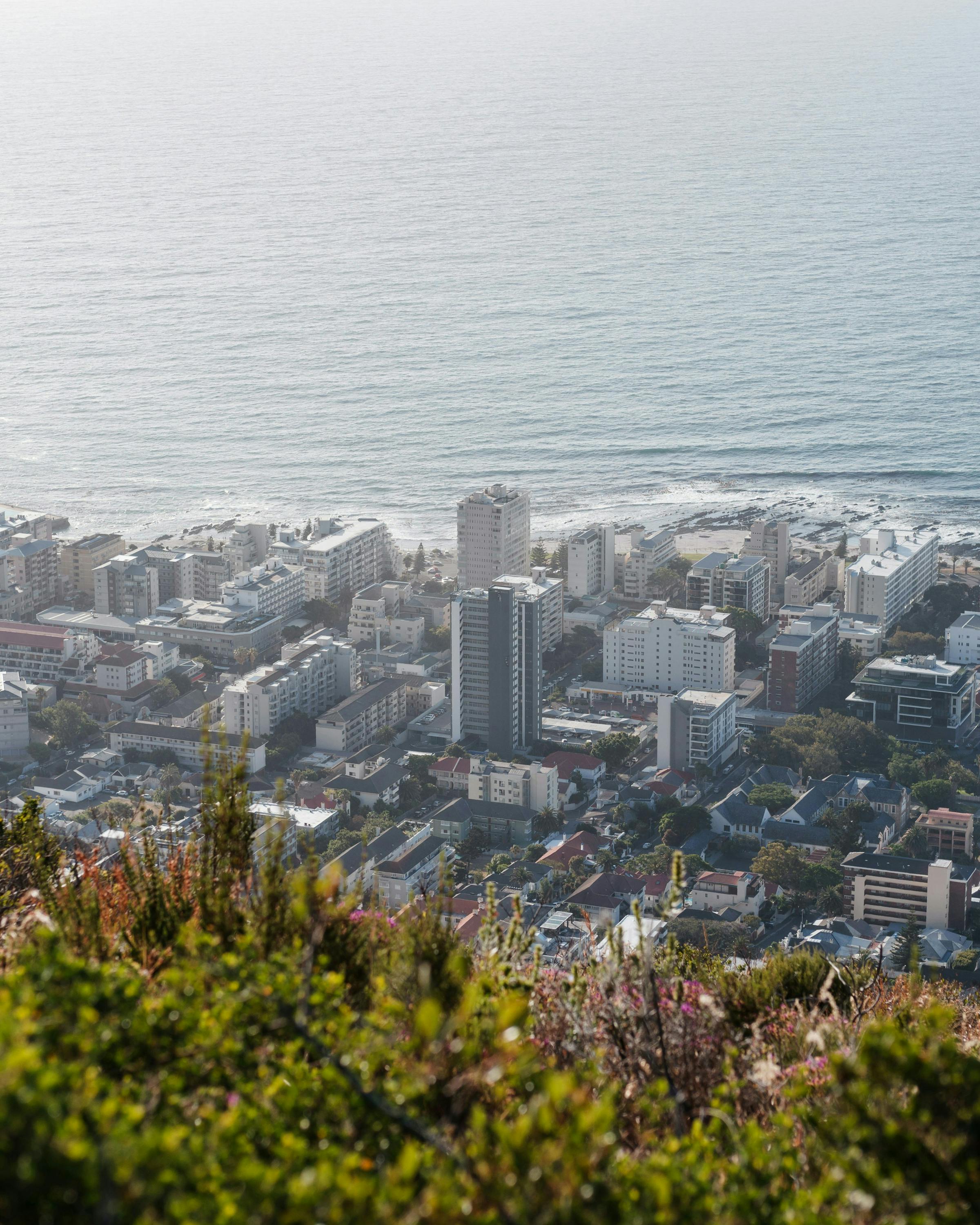 A wide view over Cape Town reveals dense neighborhoods and the Atlantic coastline stretching along the horizon.