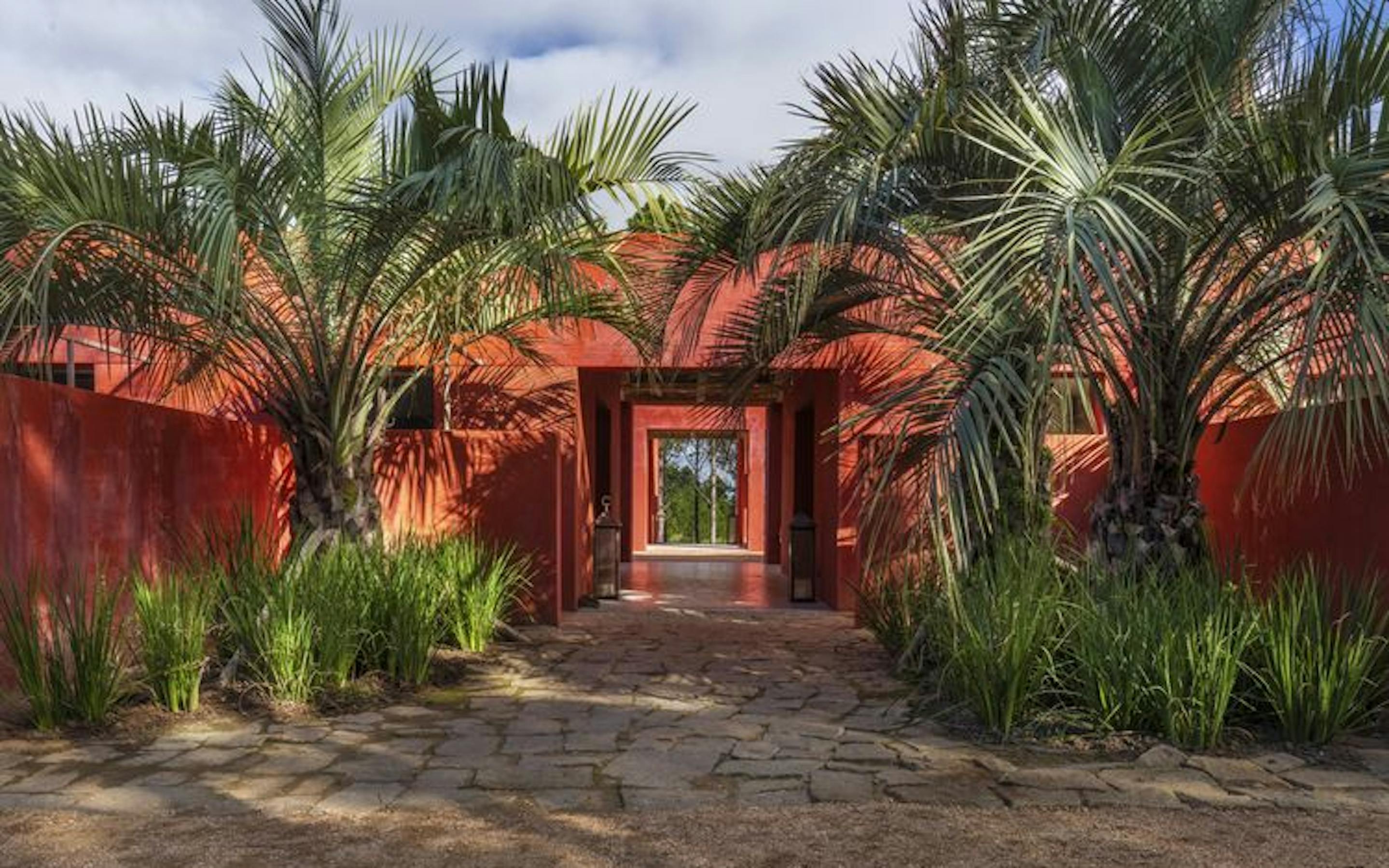 A red building surrounded by lush palm trees.