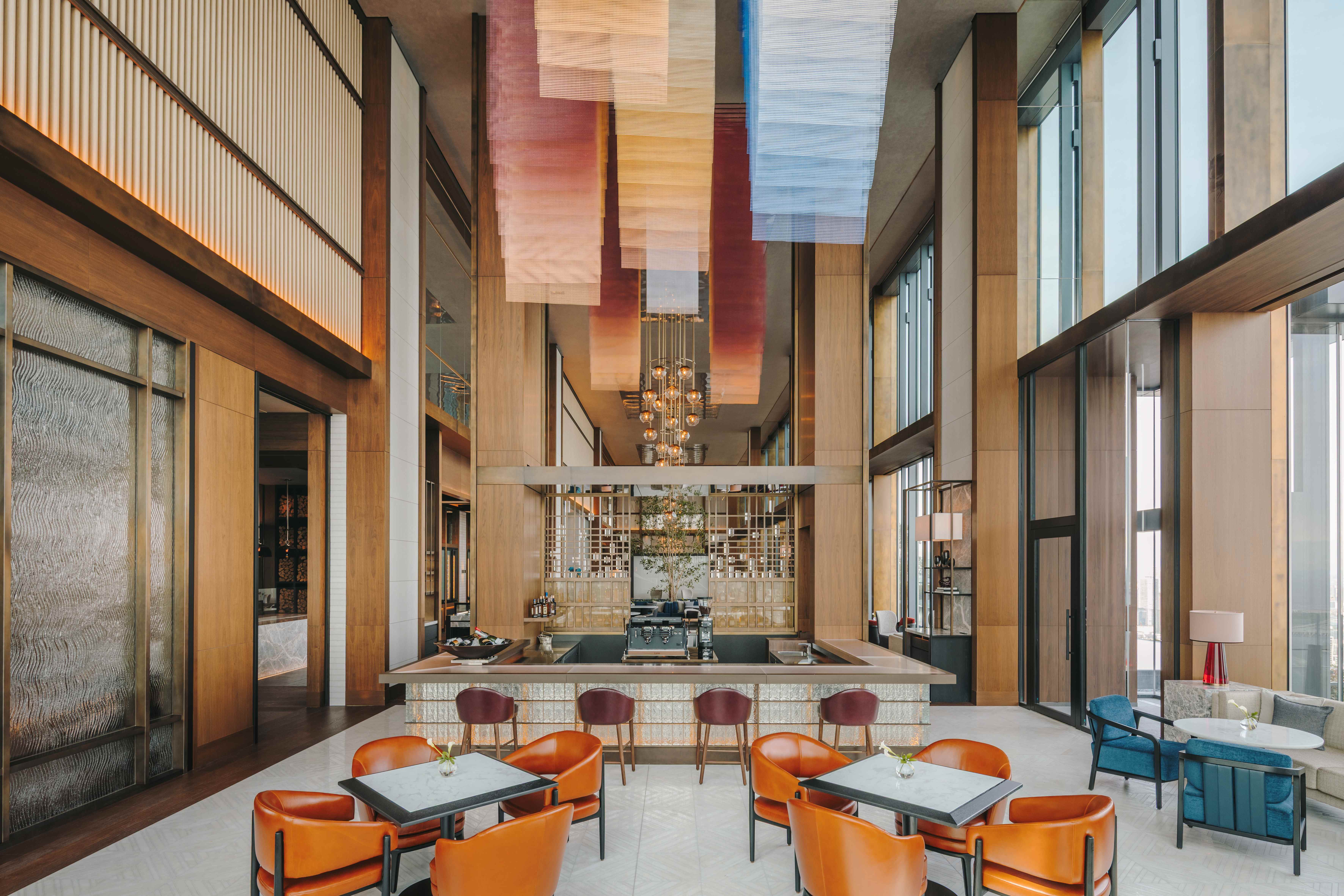 Fairmont Tokyo’s lobby lounge has soaring ceilings, warm wood walls, and seating beneath colorful fabric panels.