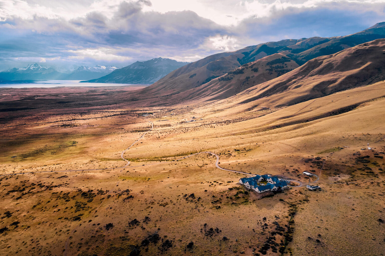 The wide Patagonian steppe near EOLO, with ochre hills and distant peaks under soft cloud.