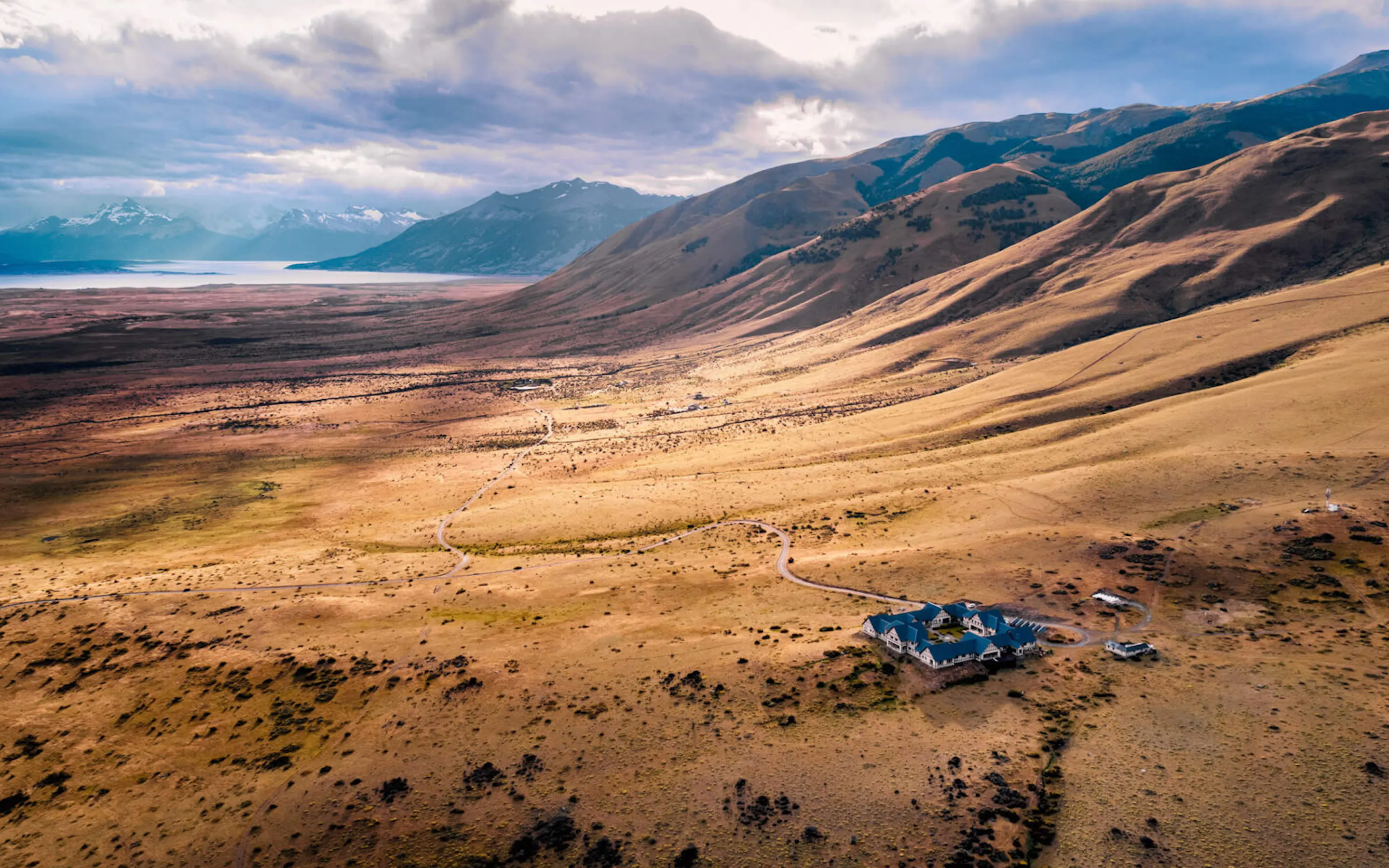 The wide Patagonian steppe near EOLO, with ochre hills and distant peaks under soft cloud.