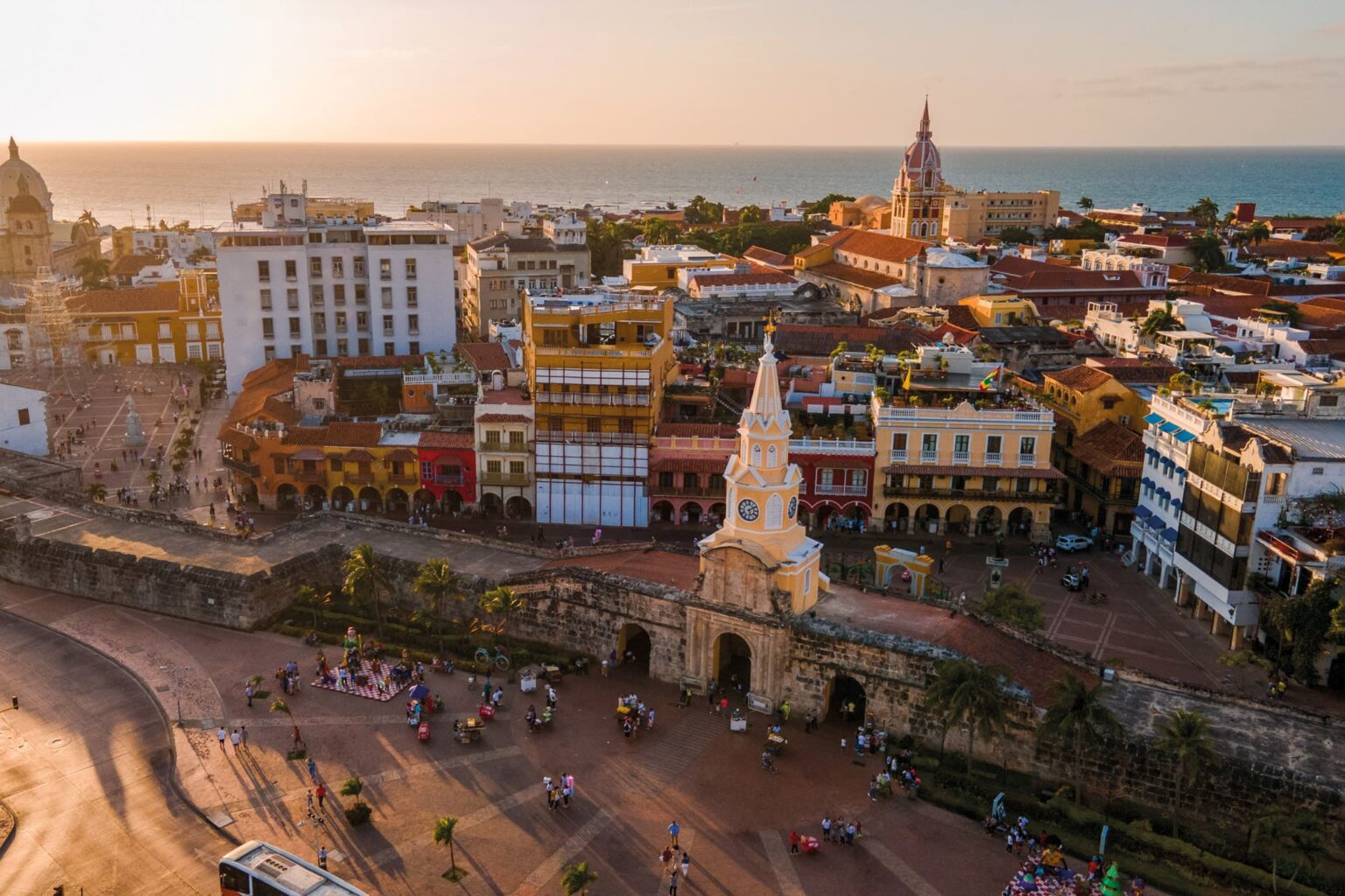 Golden light washes over Cartagena's old city, where church towers and terracotta roofs rise beside the sea.