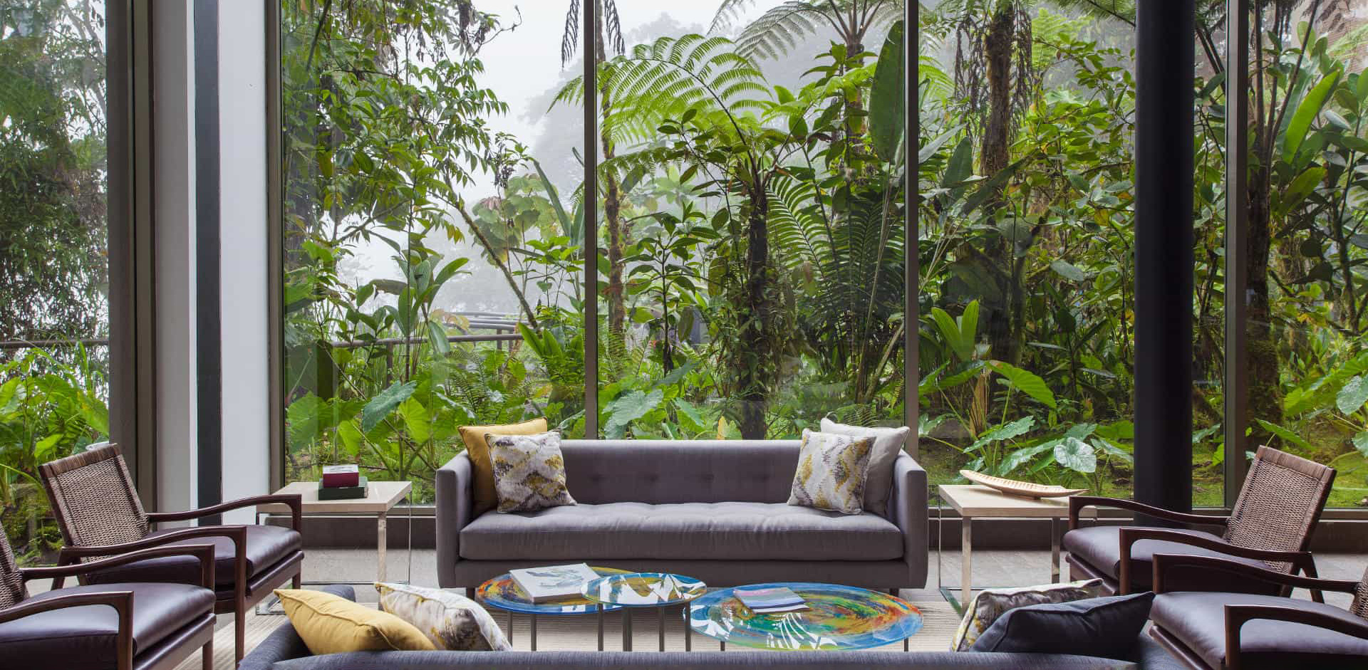 A rainforest lodge lounge framed by floor-to-ceiling windows at Mashpi Lodge, set in Ecuador's cloud forest.