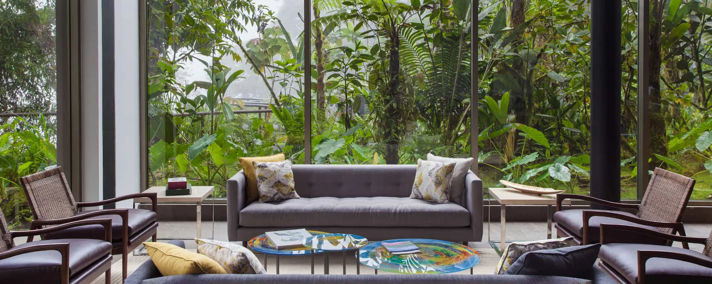 A rainforest lodge lounge framed by floor-to-ceiling windows at Mashpi Lodge, set in Ecuador's cloud forest.