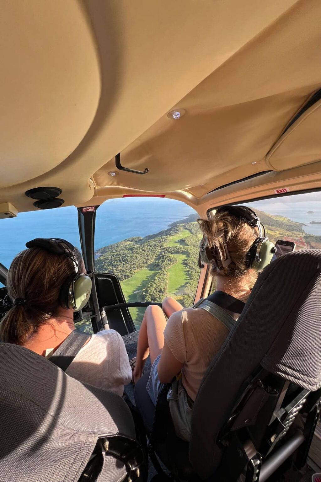 Two travelers looking out from a helicopter above a tropical coast against the backdrop of Queensland, Australia.
