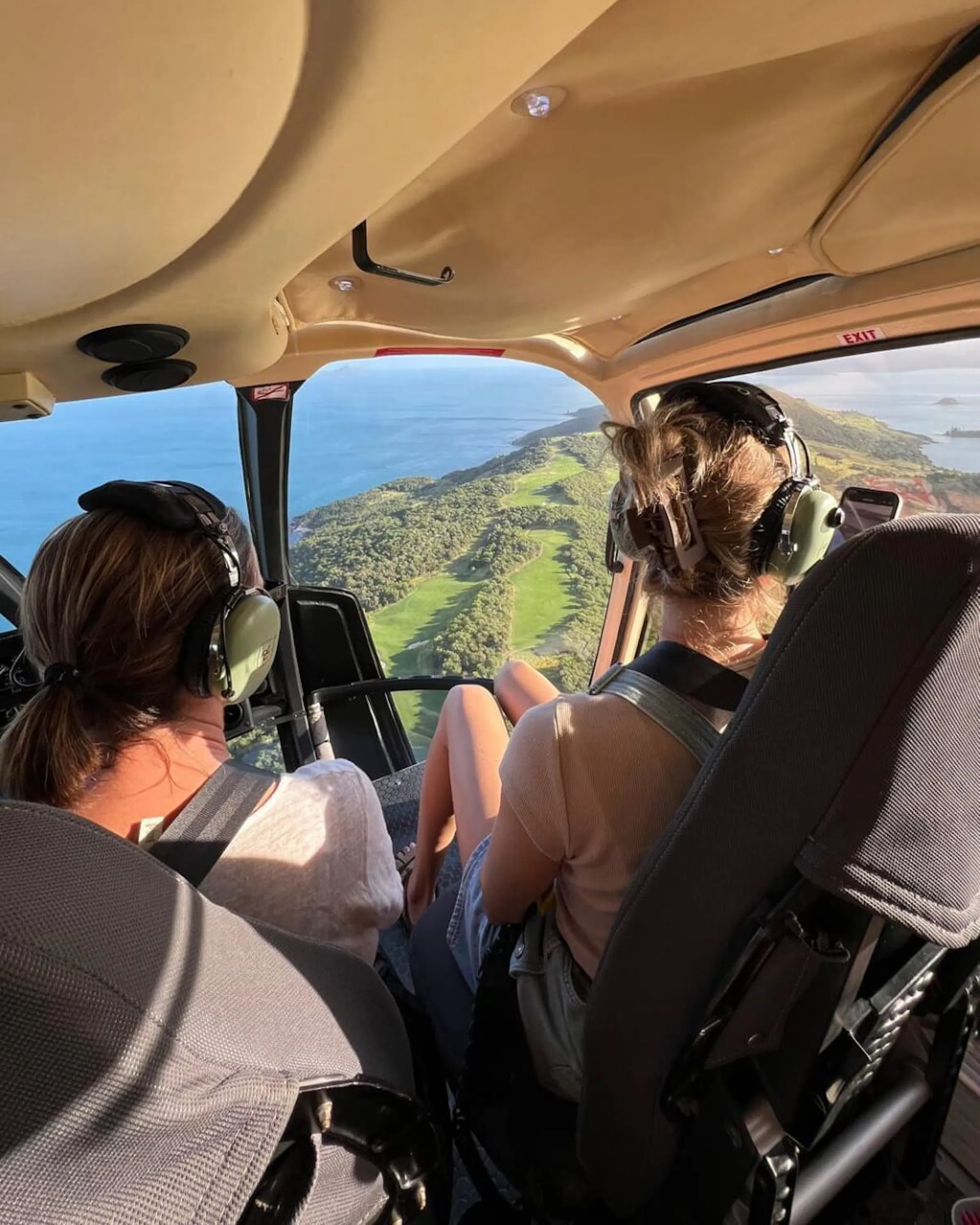 Two travelers looking out from a helicopter above a tropical coast against the backdrop of Queensland, Australia.