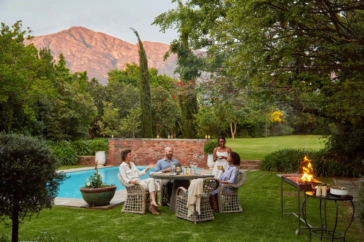 Guests gathered around a fire pit in a garden courtyard at La Cle des Montagnes in South Africa's Cape Winelands.