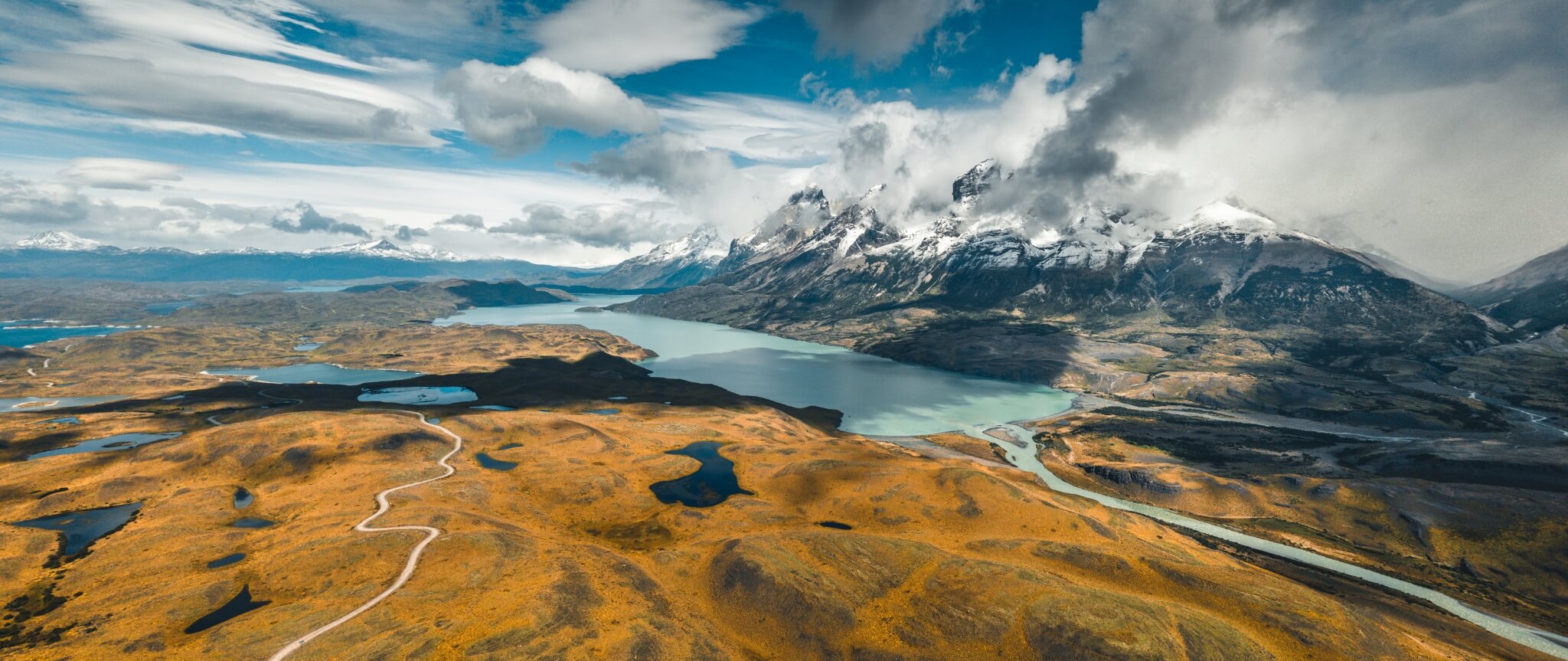Jagged peaks rise above a Patagonian valley and lake near El Chalten, with rocky slopes cutting into the sky.