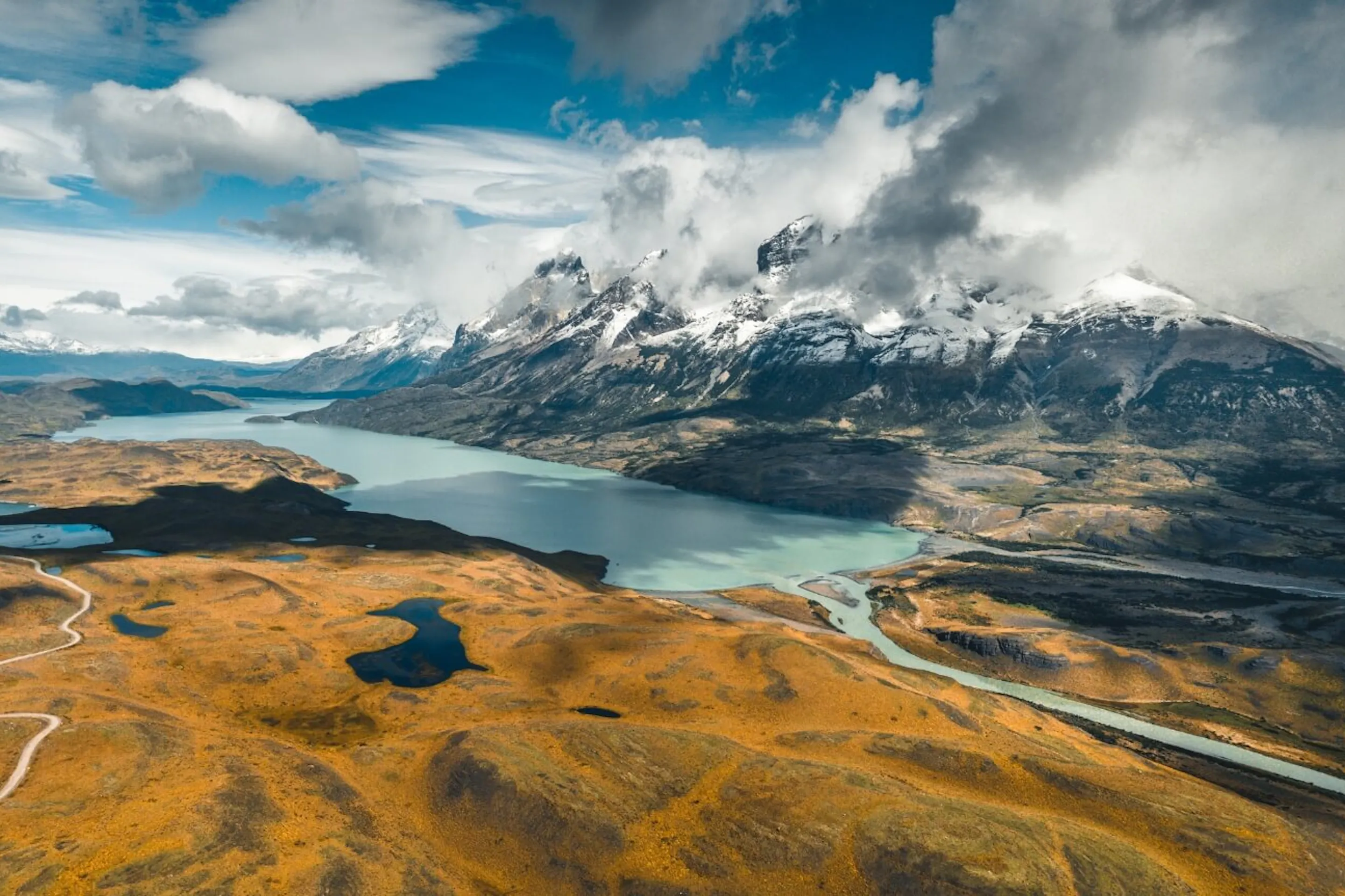Jagged peaks rise above a Patagonian valley and lake near El Chalten, with rocky slopes cutting into the sky.