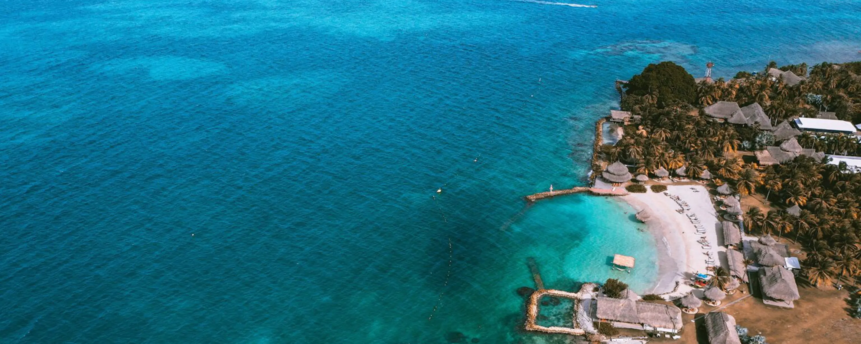 An aerial view reveals bright shallows, white sand, and a secluded lodge on Colombia's Islas San Bernardo.